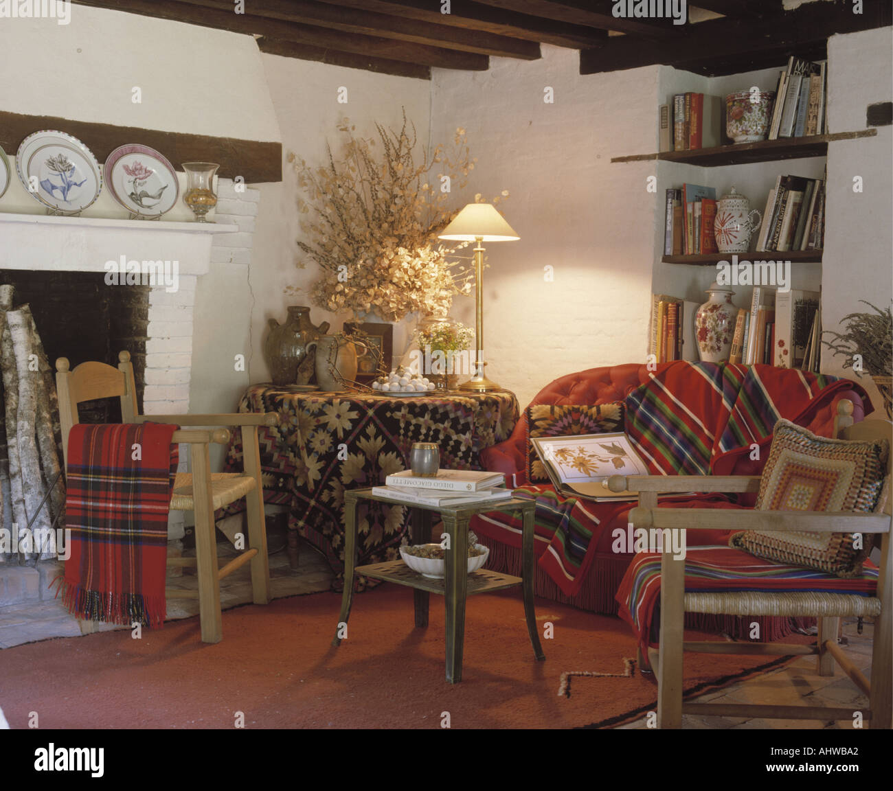 Beleuchtete Lampe und Tuch auf dem Tisch in der Ecke des Wohnzimmers gemütliche Hütte mit roten Sofa unter Alkoven Regale Stockfoto