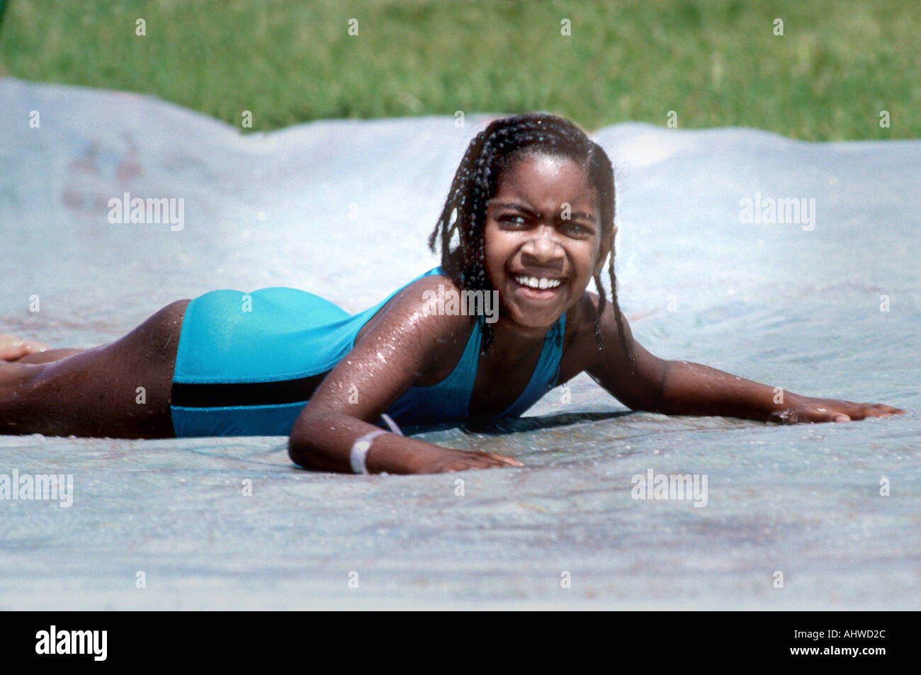 8 jährige schwarze Mädchen spielt auf einem Boden Wasserrutsche Stockfoto
