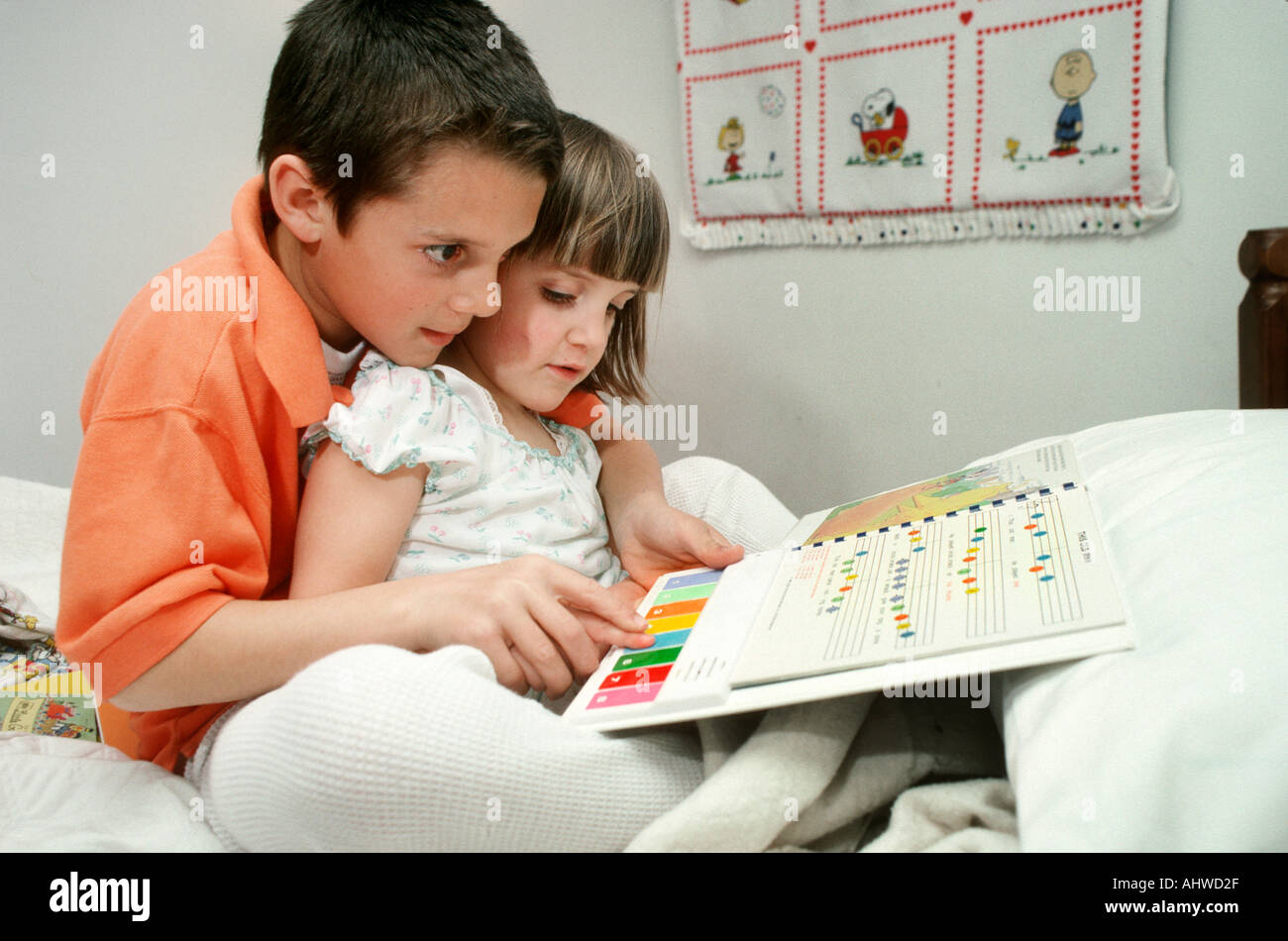 9 Jahre alter Bruder hilft Schwester ihr Song-Buch lernen Stockfoto