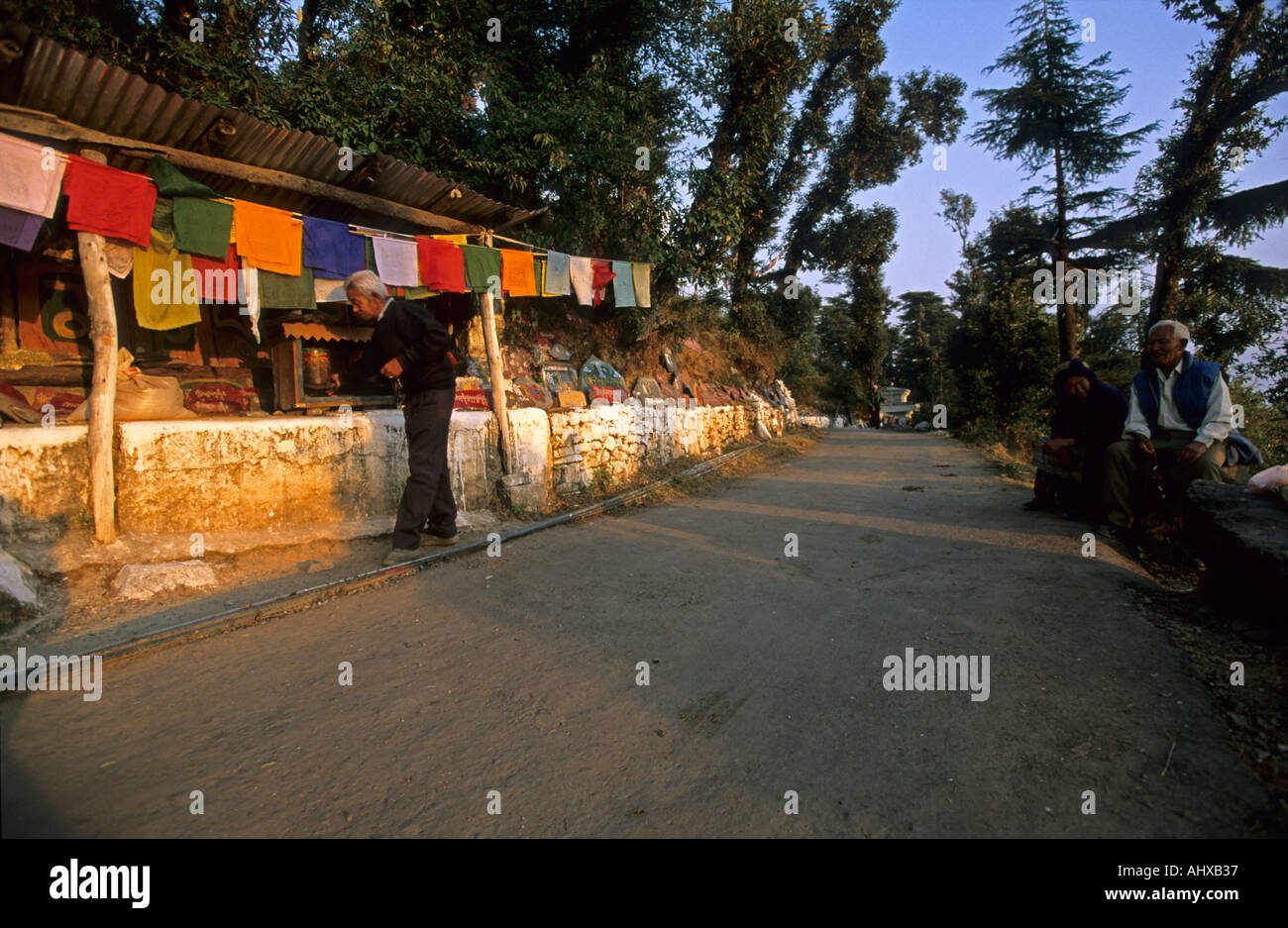 Pilger auf der Kora Route um den Dalai Lama Seat in Dharamsala, Himachal Pradesh, Indien. Buddhistische Gebetsfahnen säumen den malerischen Bergpfad bei Sonnenuntergang. Stockfoto
