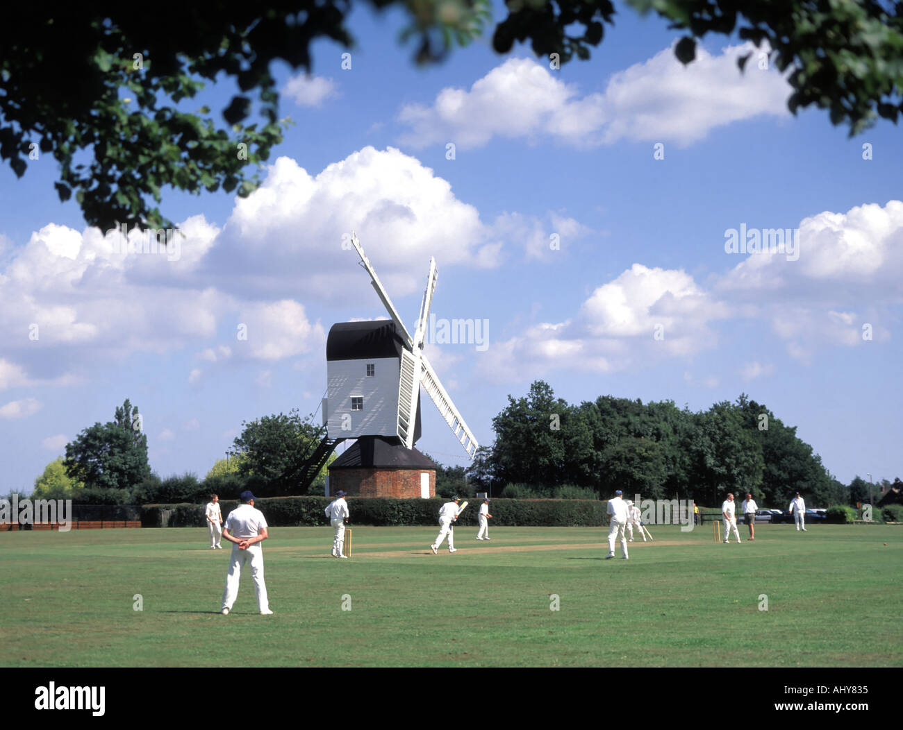 Iconic fundamentale England idyllisches Dorf grün Cricket Match bowler Batsman & Feldspieler Mountnessing Post Mühle darüber hinaus in der Landschaft von Essex UK Stockfoto