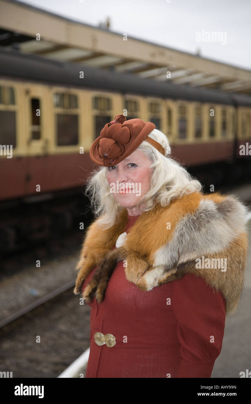 Reife Frau tragen Fox Pelz Stola Vintage Mode stehen auf Plattform warten auf Zug in Pickering Bahnhof, Yorkshire. Stockfoto