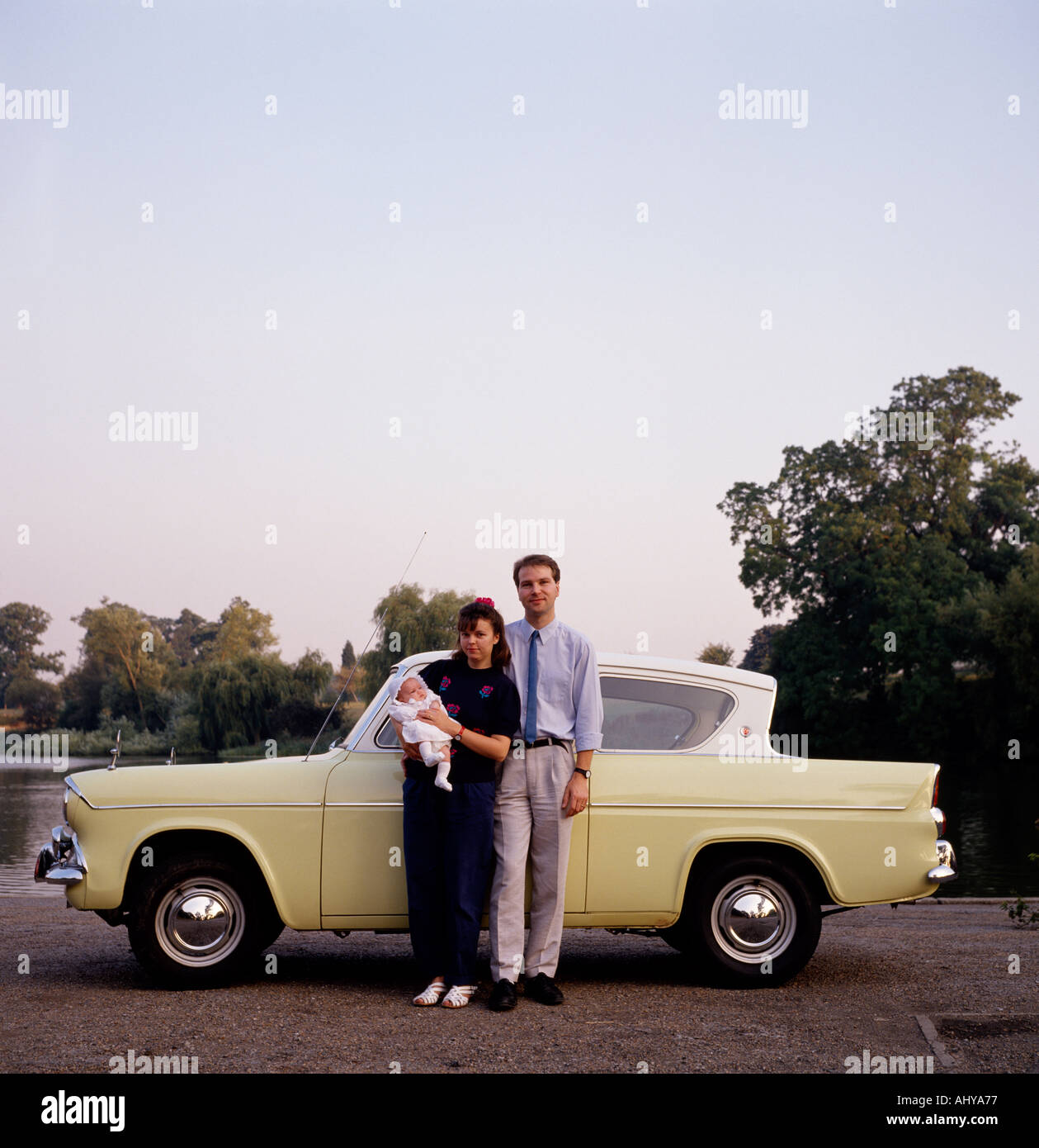 Eine junge Familie mit ihrem Auto Ford Anglia in England in Großbritannien im Vereinigten Königreich Großbritannien. Stockfoto