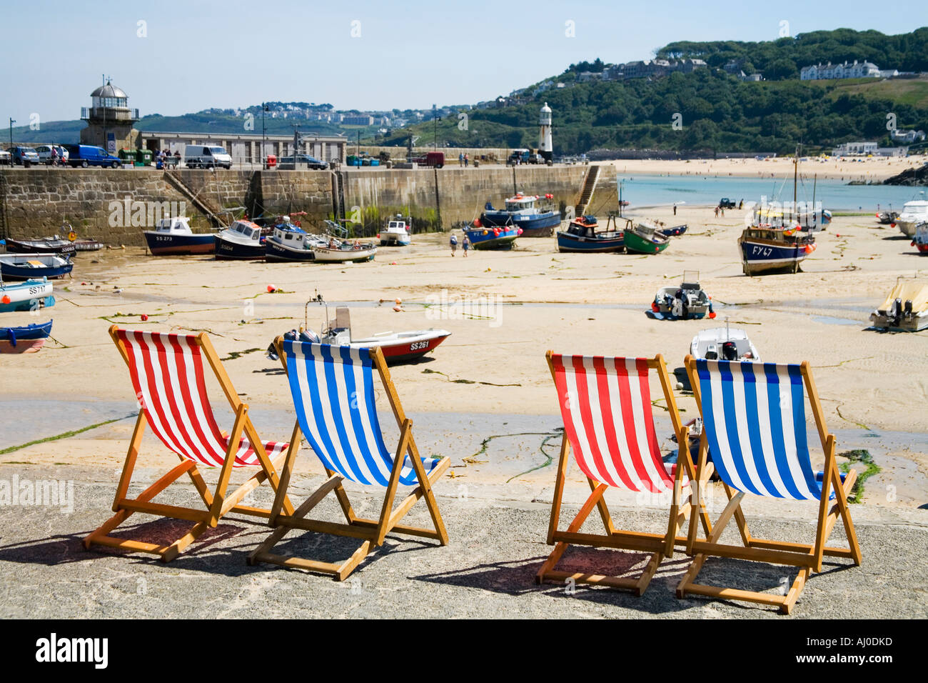 Vier 4 leeren Liegestühle Liegestühle an sonnigen Sommertag auf der Hafenmauer in St Ives Cornwall England UK United Kingdom GB Stockfoto