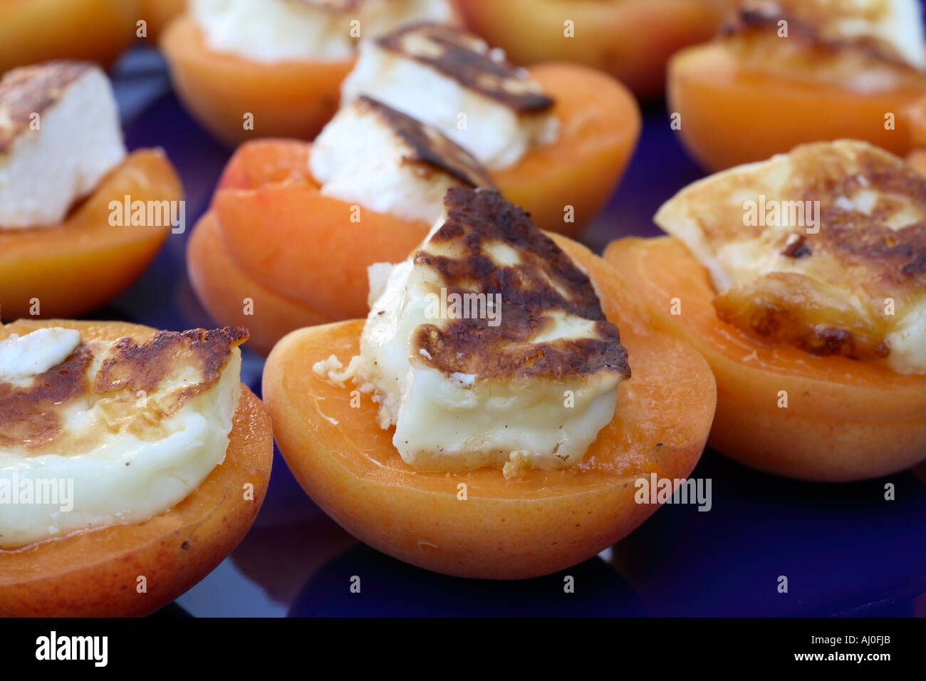 Aprikosen mit gegrilltem Halloumi Käse auf der blauen Platte. Stockfoto
