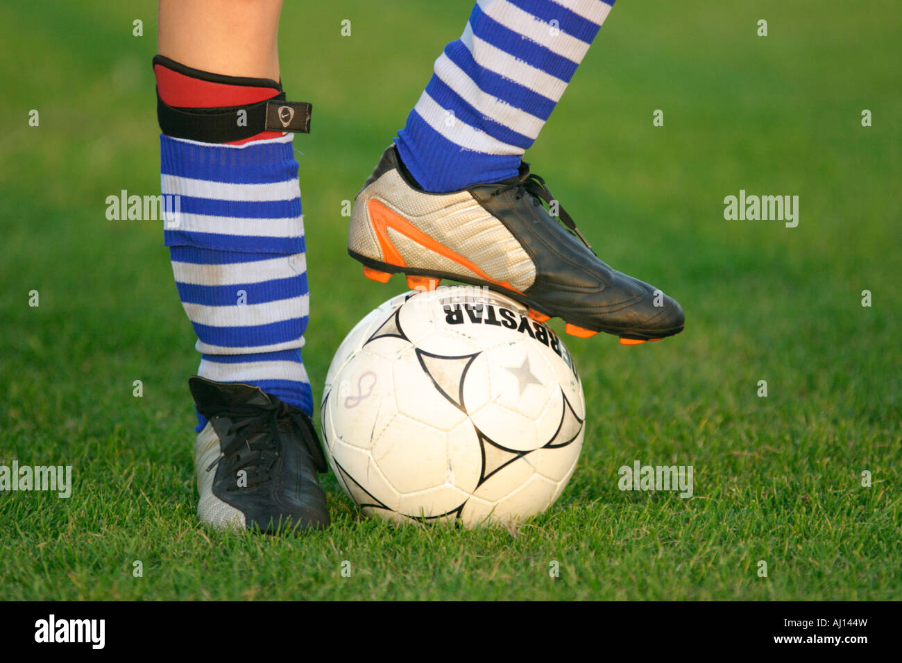 Detail eines Fußballs und Beine mit Fußballschuhe und Socken bekleidet Stockfoto