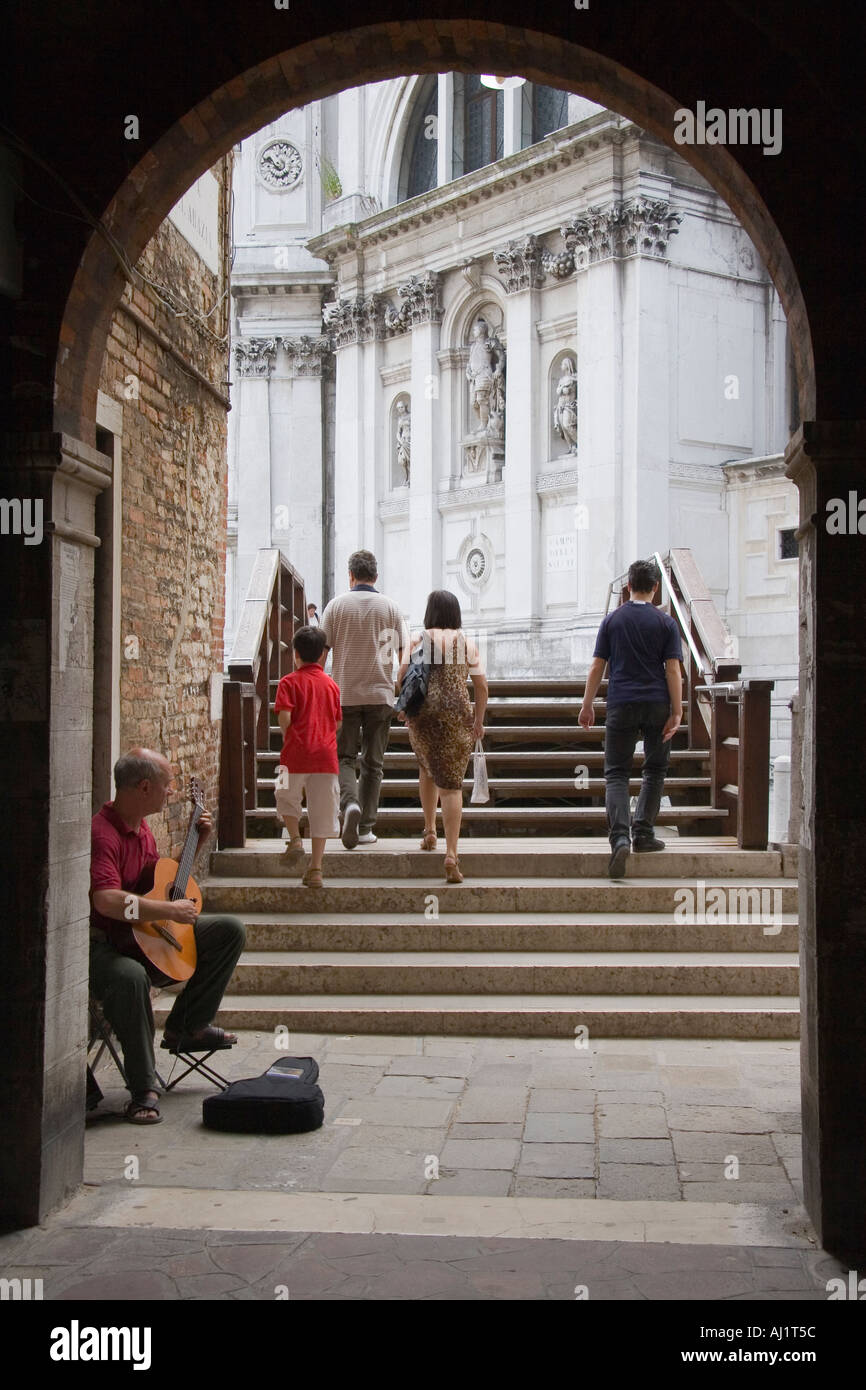 Man Gitarre spielen unter Torbogen von Brücke mit Santa Maria Della Salute-Kirche im Hintergrund Venedig Italien Stockfoto