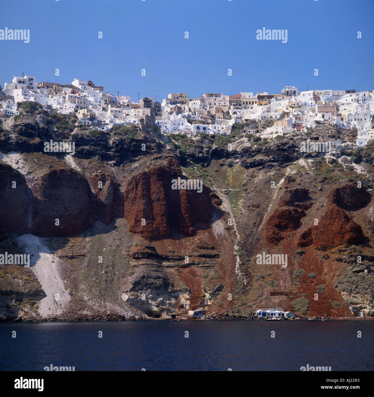 Blick vom Meer von Oia Dorf erstreckt sich entlang der roten kargen vulkanischen Klippen auf den griechischen Inseln Santorini Stockfoto