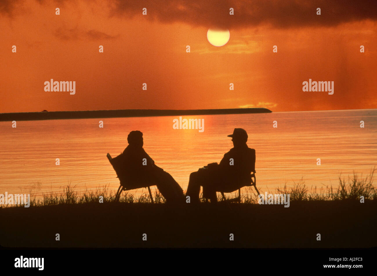 Älteres paar sitzen beobachten Sonnenuntergang am Lake Michigan Stockfoto