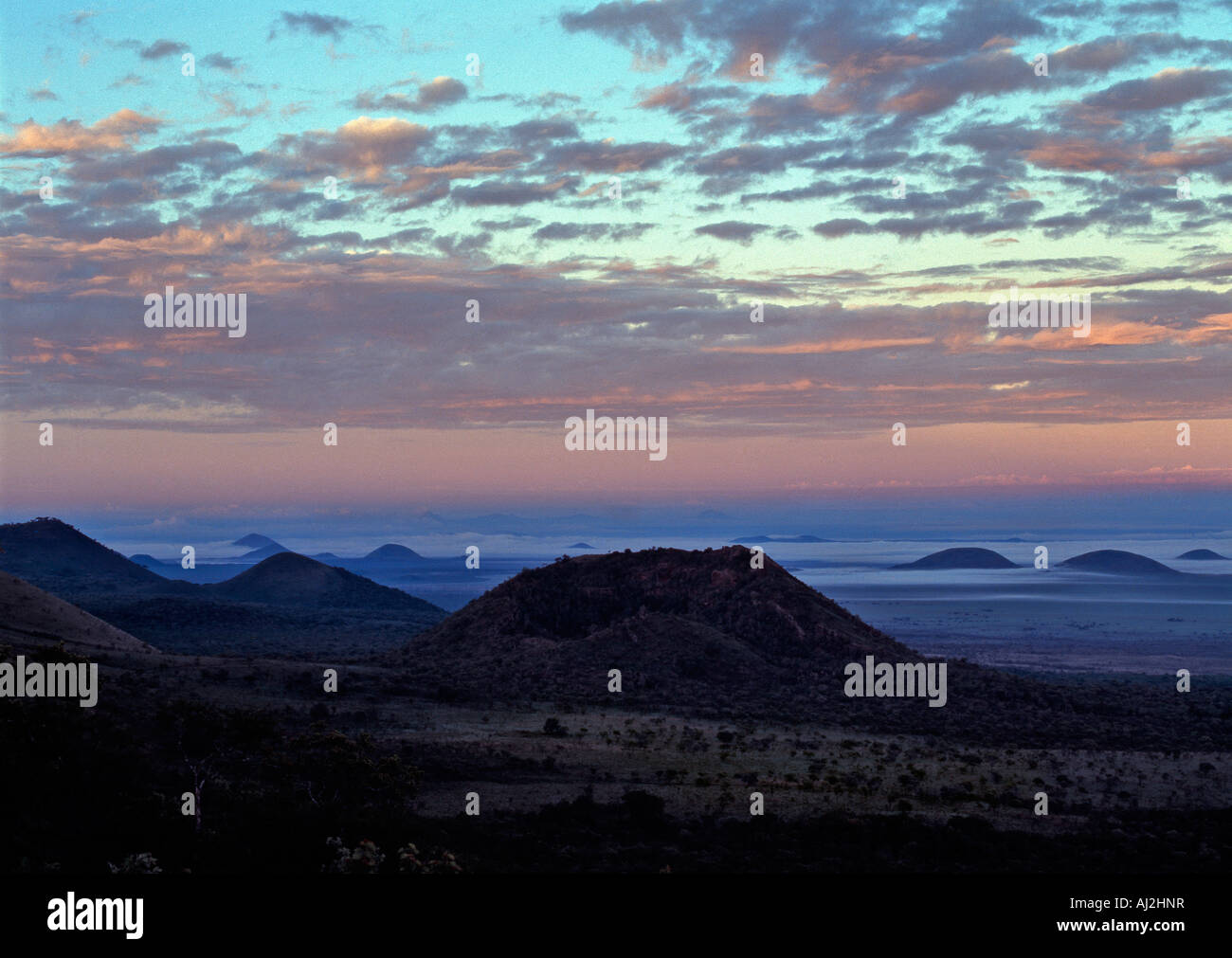 Dawn Himmel mit niedrigen Wolken umliegenden Vulkankegeln nahe der Chyulu Hills. Stockfoto