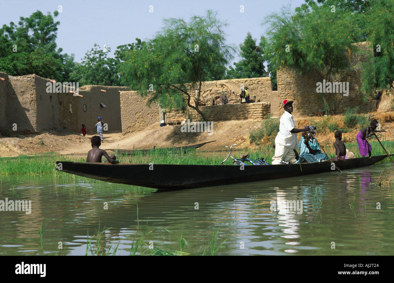 Lokale Passagiere des Bozo-Stammes auf einem Pirogue oder hölzernen Flussboot, das über den geschwollenen Niger Fluss in Dagua Womina, Mali, Westafrika, gefahren wird Stockfoto