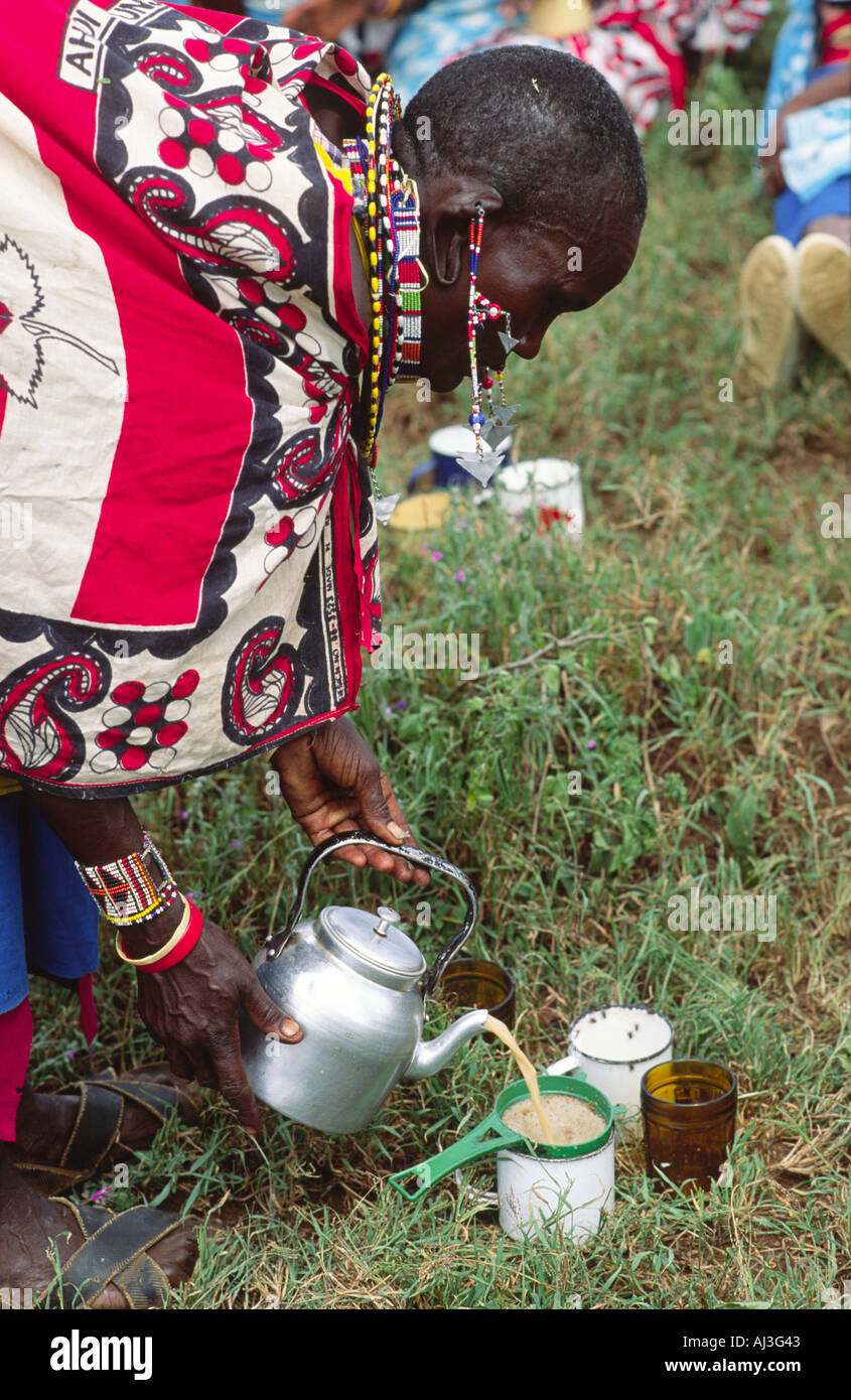 Maasai Dame in traditionellen Kleidern macht Tee draußen bei einem Frauen-Kooperations-Treffen. Kajiado, Kenia Stockfoto