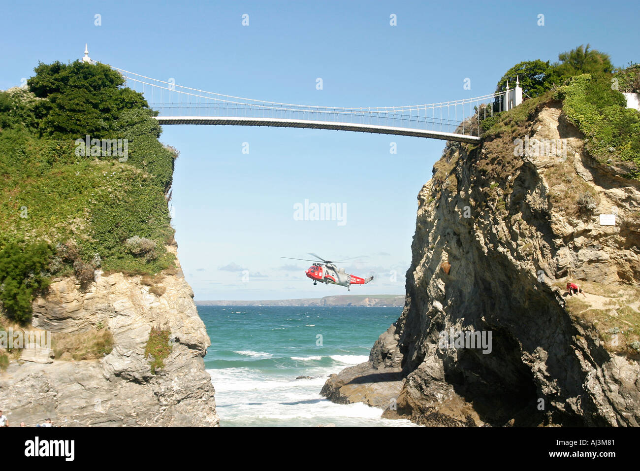 Hubschrauber-Rettung im Meer vor der Küste Newquay Cornwall. Zwischen zwei Felsen, die durch eine Hängebrücke verbunden betrachtet Stockfoto