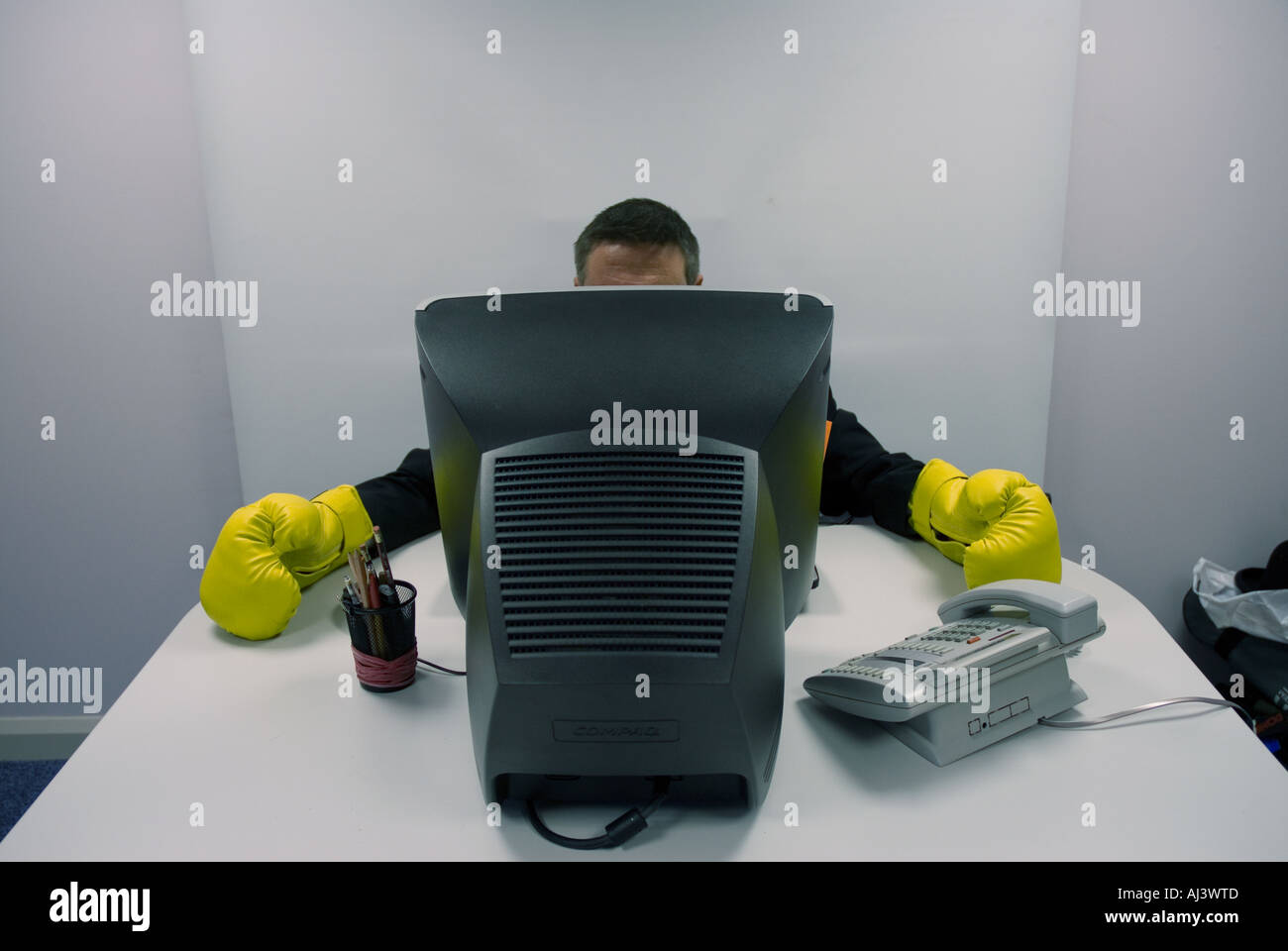 Mann trägt Boxhandschuhe Blick auf Computer, Büro Stress, harte Arbeit, Ärger im Büro Stockfoto