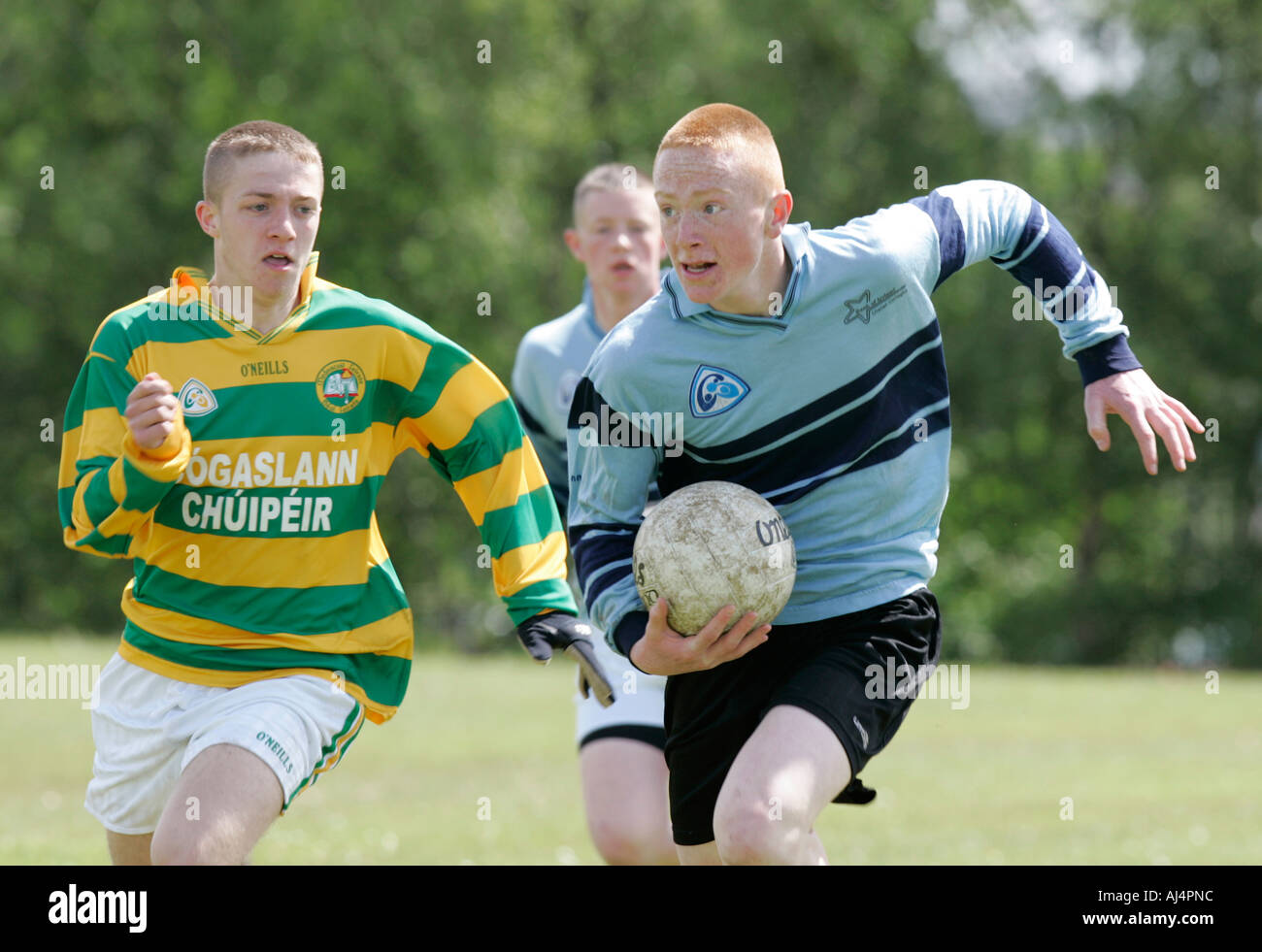 Aktion von Schuljunge Gälischer Fußballspieler läuft mit dem Ball wird weiter verfolgt-Belfast-County Antrim-Nordirland Stockfoto