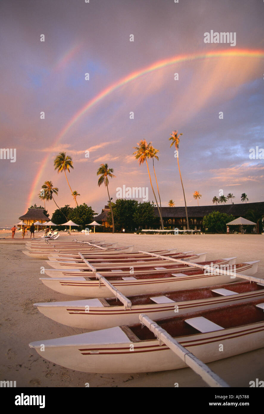 Französisch-Polynesien Moorea Regenbogen bei Sonnenuntergang über Ausleger-Kanus am Strand Stockfoto