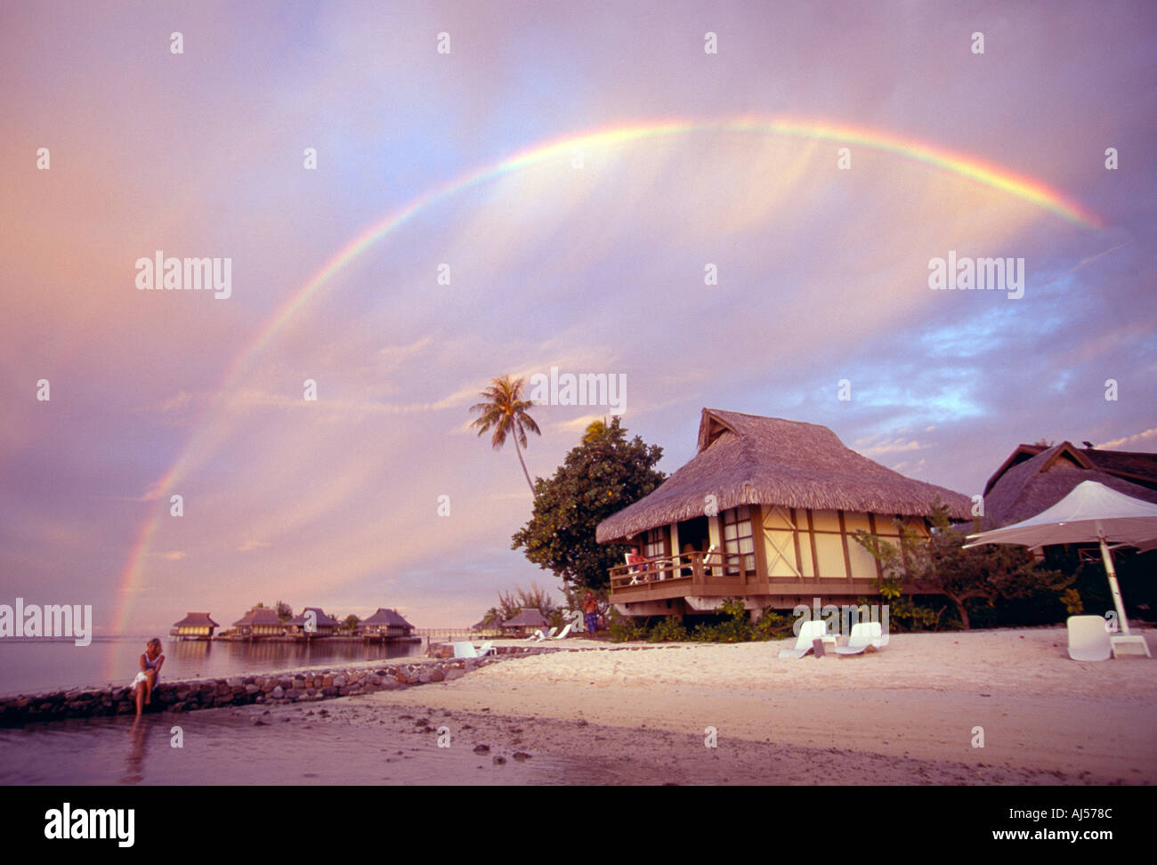 Französisch-Polynesien Moorea Regenbogen am Sonnenuntergang über Strandbungalows hängen Stockfoto