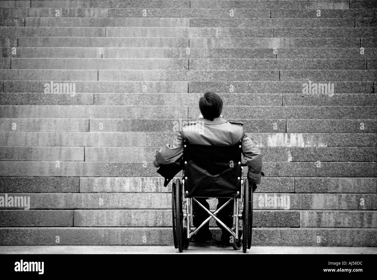 Schwarze und weiße behinderte Menschen im Rollstuhl, eine Treppe, ein unüberwindliches Hindernis Stockfoto