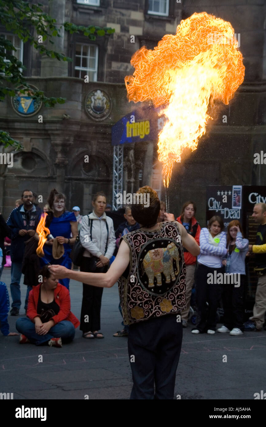 Ein Feuerschlucker Unterhaltung Menschen durch Einblasen von Flammen in die Luft auf dem Edinburgh Festival Fringe Royal Mile, Schottland. Stockfoto