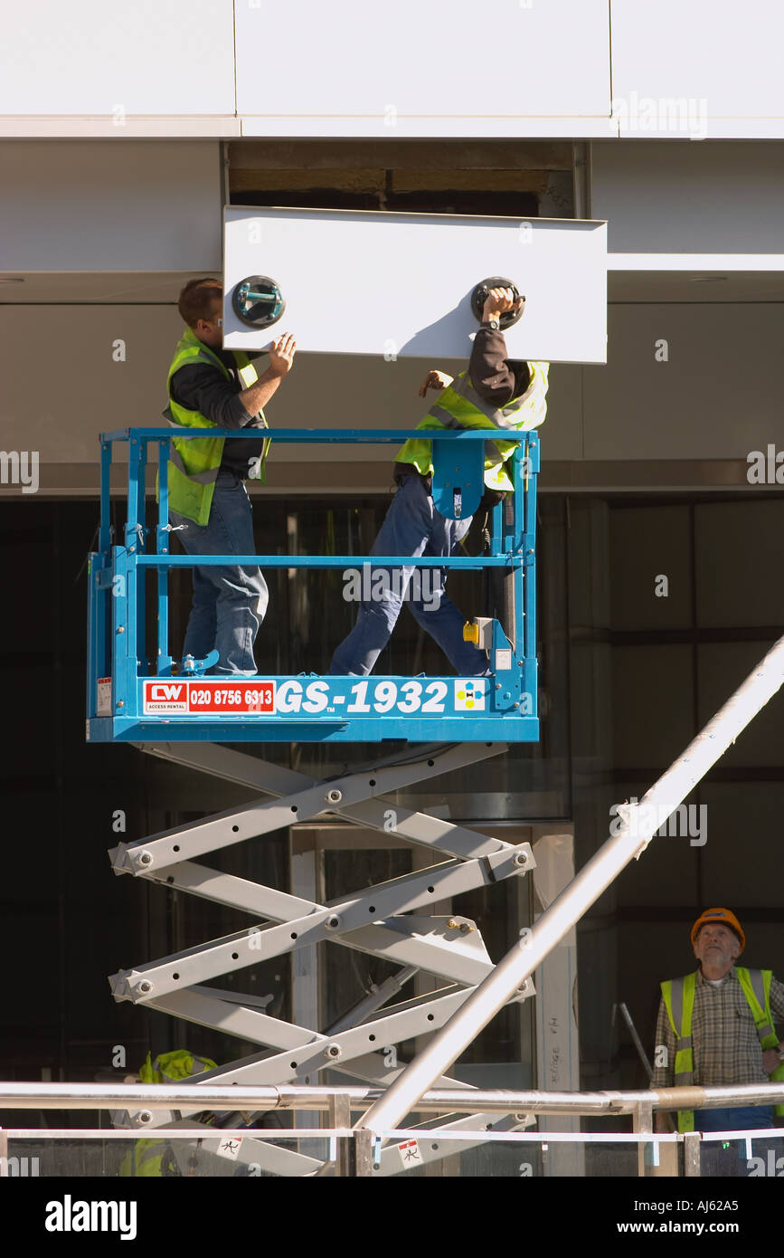 Arbeiter auf Schere heben anbringen Metall-Cladding, neues Bürogebäude Stockfoto