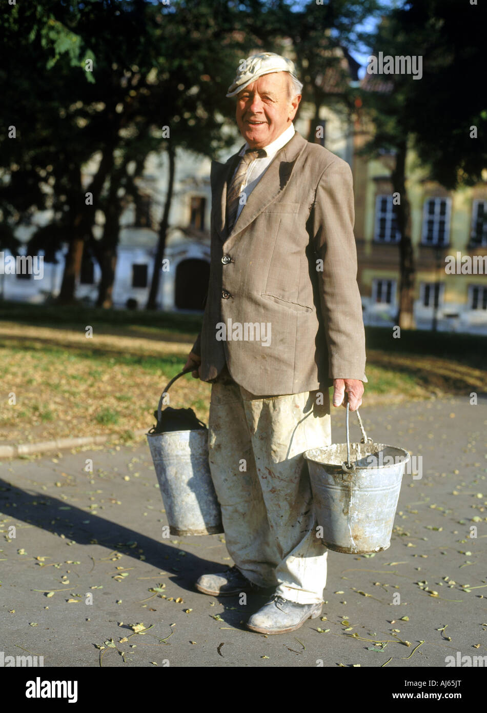 Glückliche ältere Mann geht zur Arbeit mit Farbe und Putz Eimer in Tschechien Stockfoto