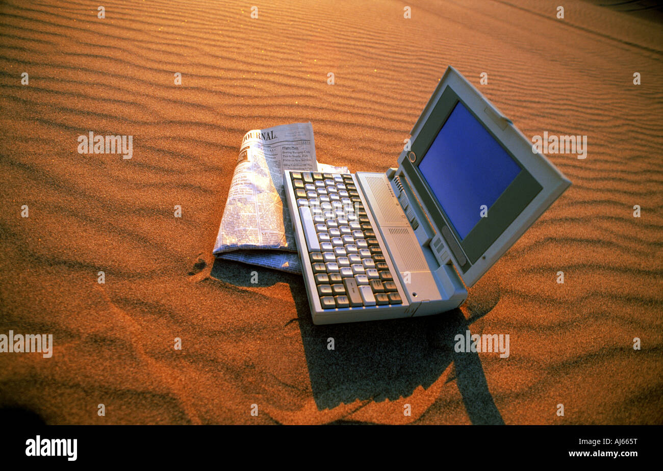 Laptop-Computer und Wall Street Journel sitzen auf Sanddüne im Abendlicht Stockfoto