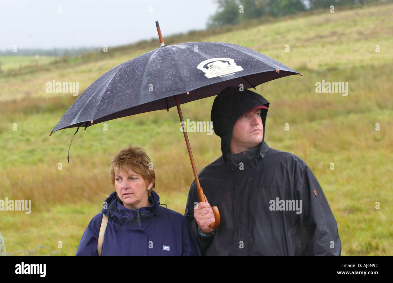 Zuschauern Unterschlupf unter einem Sonnenschirm auf der Welt Bog Schnorcheln Meisterschaften Llanwrtyd Wells Powys Wales UK GB Stockfoto