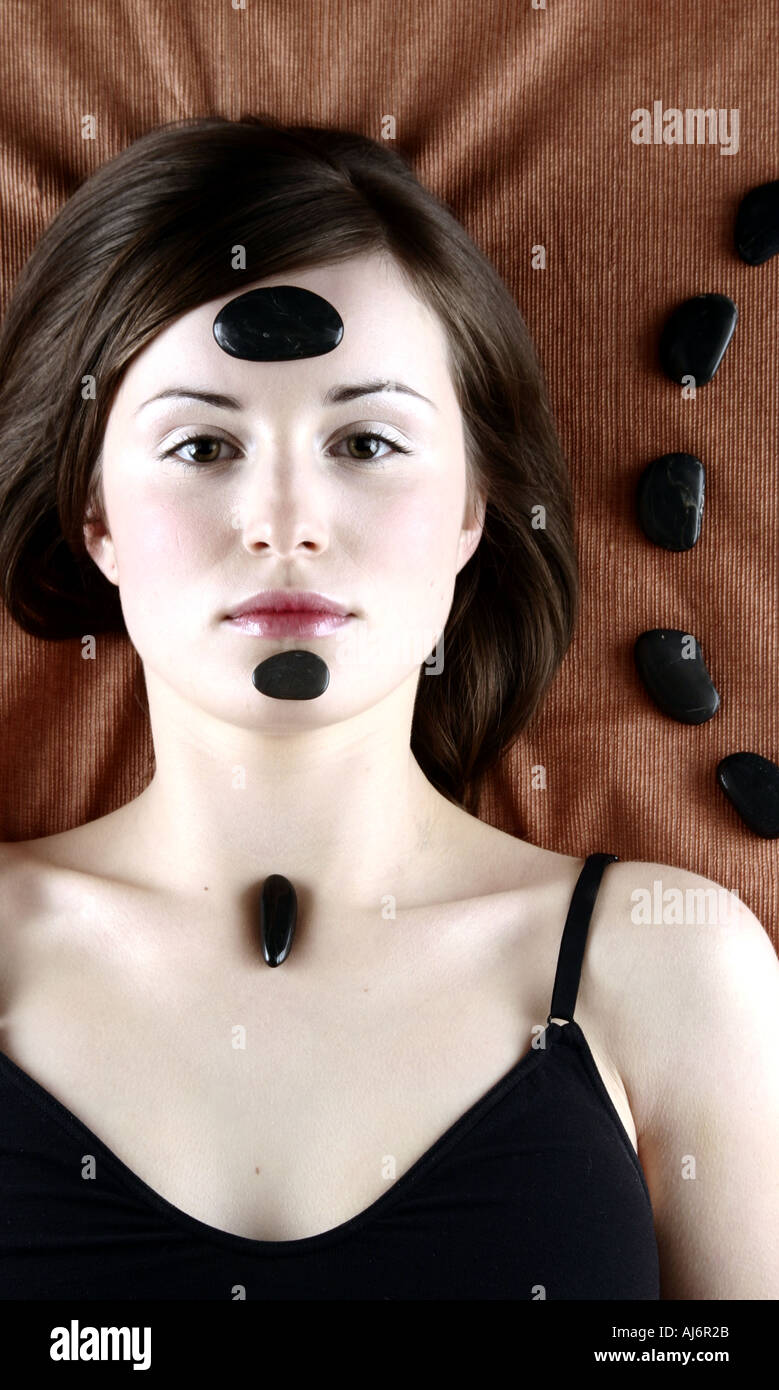 Frau 20 25 Brünette dunklen Haaren kastanienbraunen Augen Haare ernst meditativen Entspannung liegen entspannt relaxen Stein Steinen Stockfoto