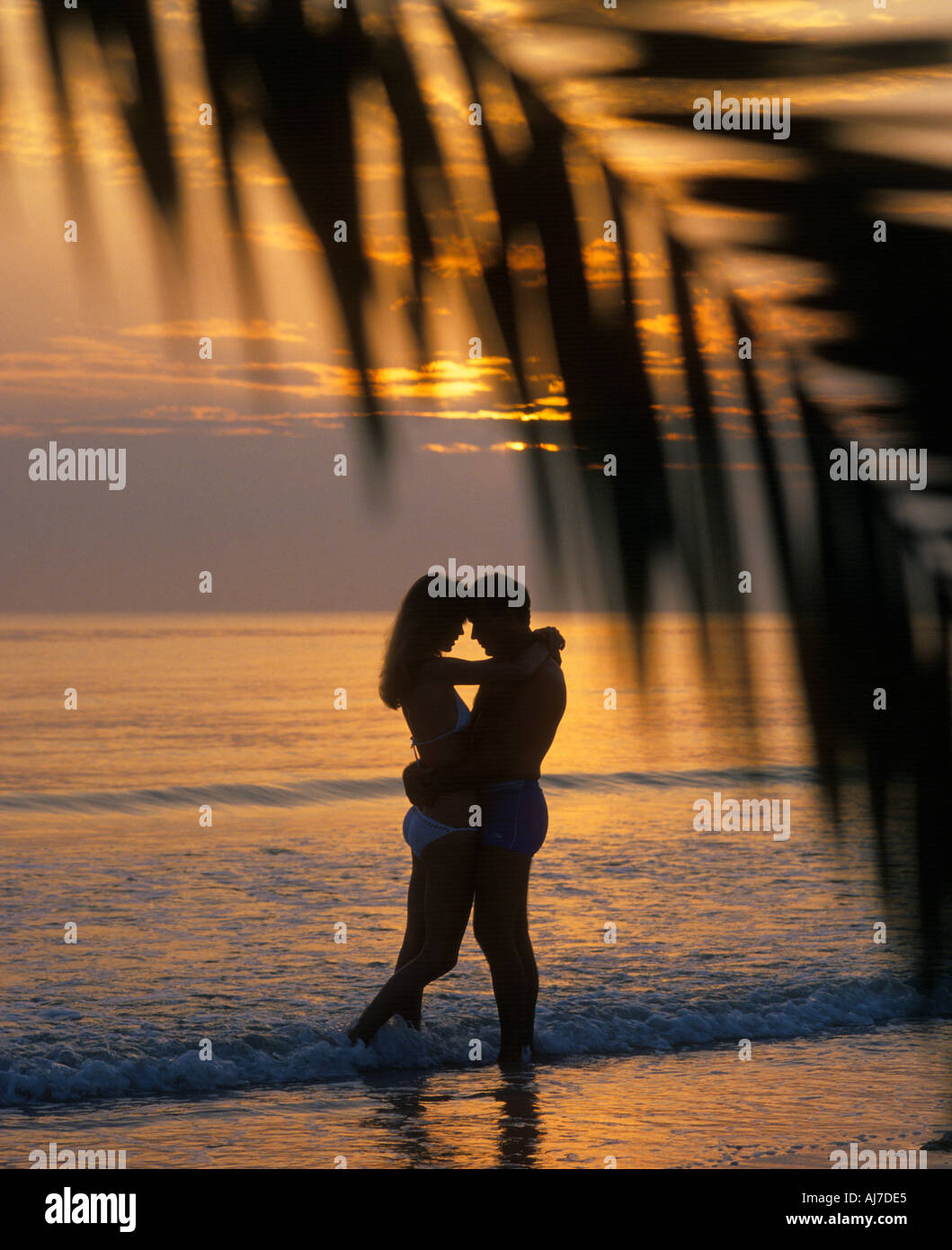 romantisches Paar umarmt am Strand bei Sonnenuntergang Stockfoto