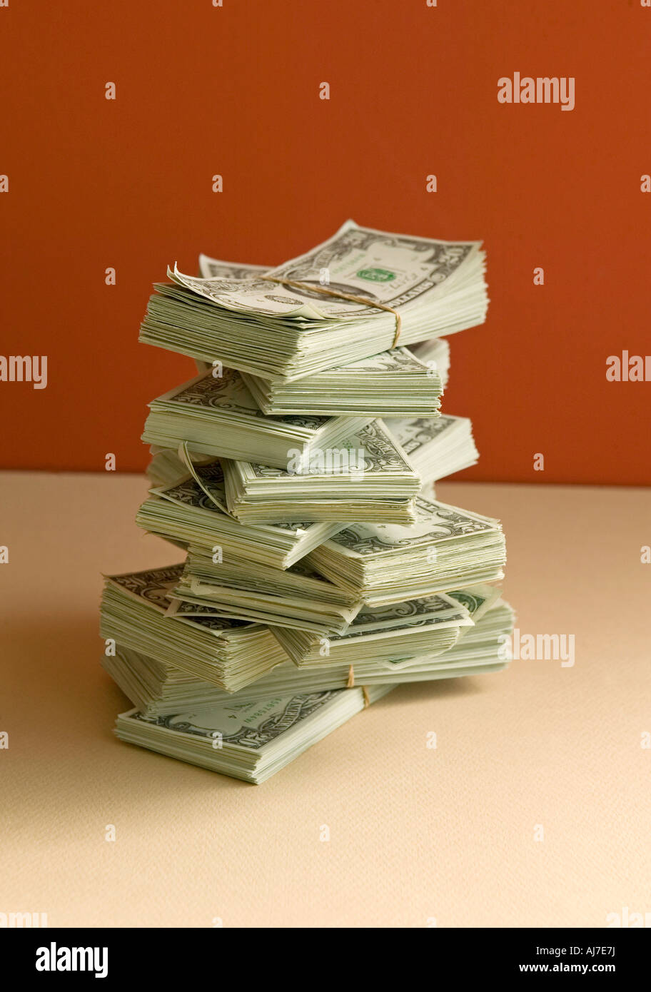 Stapel von Geld in Haufen mit Dollar auf orangem Hintergrund Stockfoto