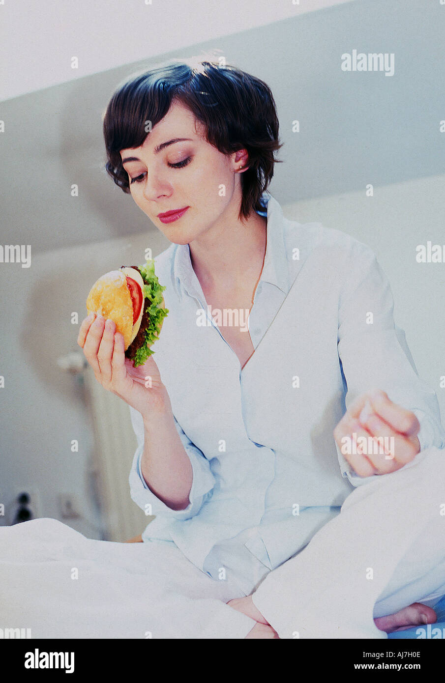 flache Innenraum Frau Mädchen 25 30 junge Brünette kurze Haare sitzen essen Essen Essen sandwich Stockfoto