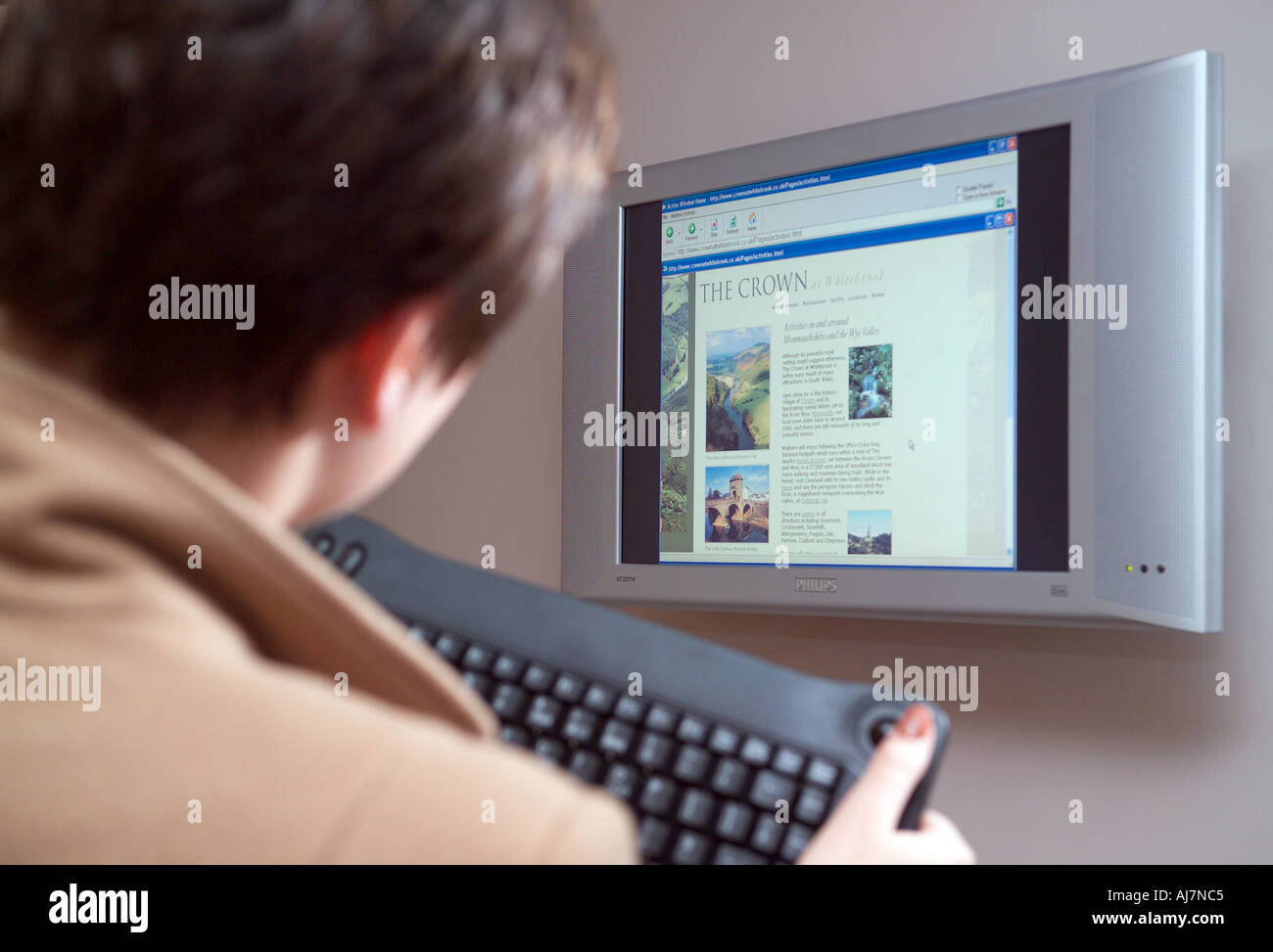 Frau mit Funktastatur mit Wand montierte Computer-Bildschirm Stockfoto