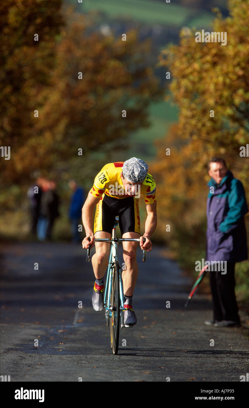 Einziger Wettbewerber Rennen selbst in einem herbstlichen Fahrrad Straße Rennen Großbritannien, durch ein paar Zuschauer Stockfoto