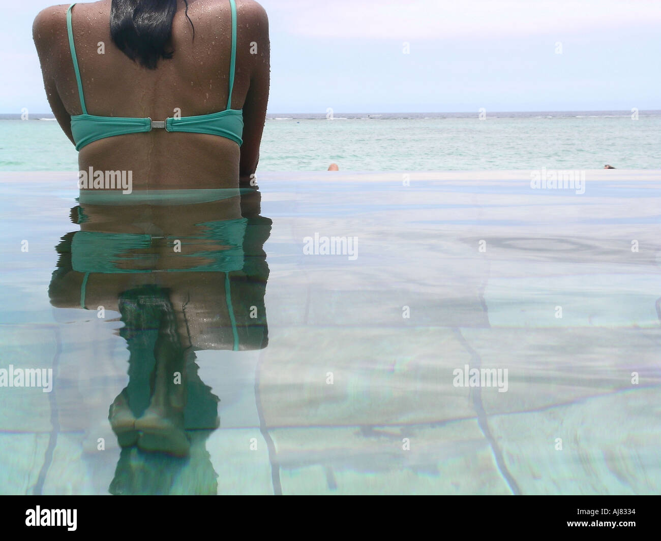 Frau im Bikini im Infinity-Pool mit Meer im Hintergrund, Mauritius Stockfoto