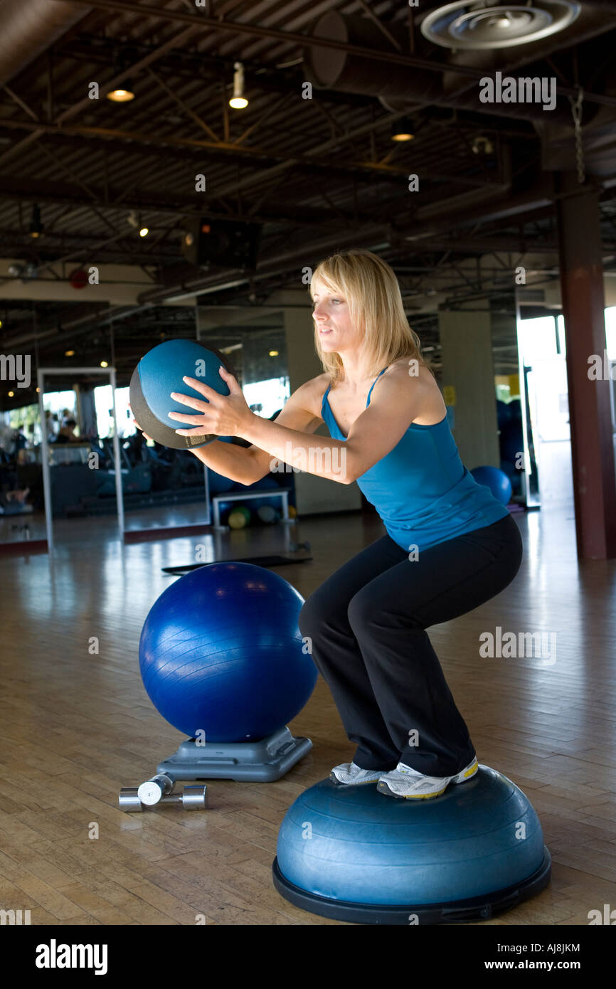 fit Fitness female Mädchen Turnen in der Turnhalle. Bein-Training auf einem Bosu ball Stockfoto