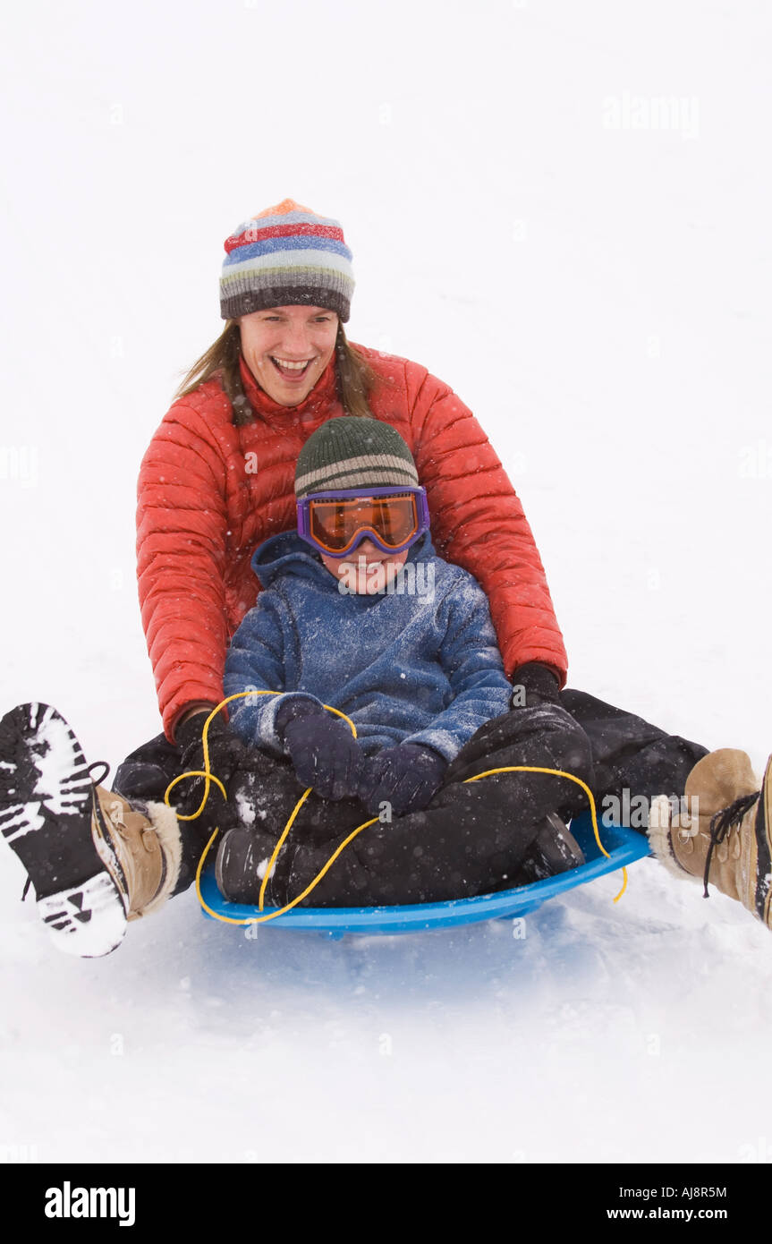 Mutter und Sohn Rodeln bei Schneesturm. Stockfoto