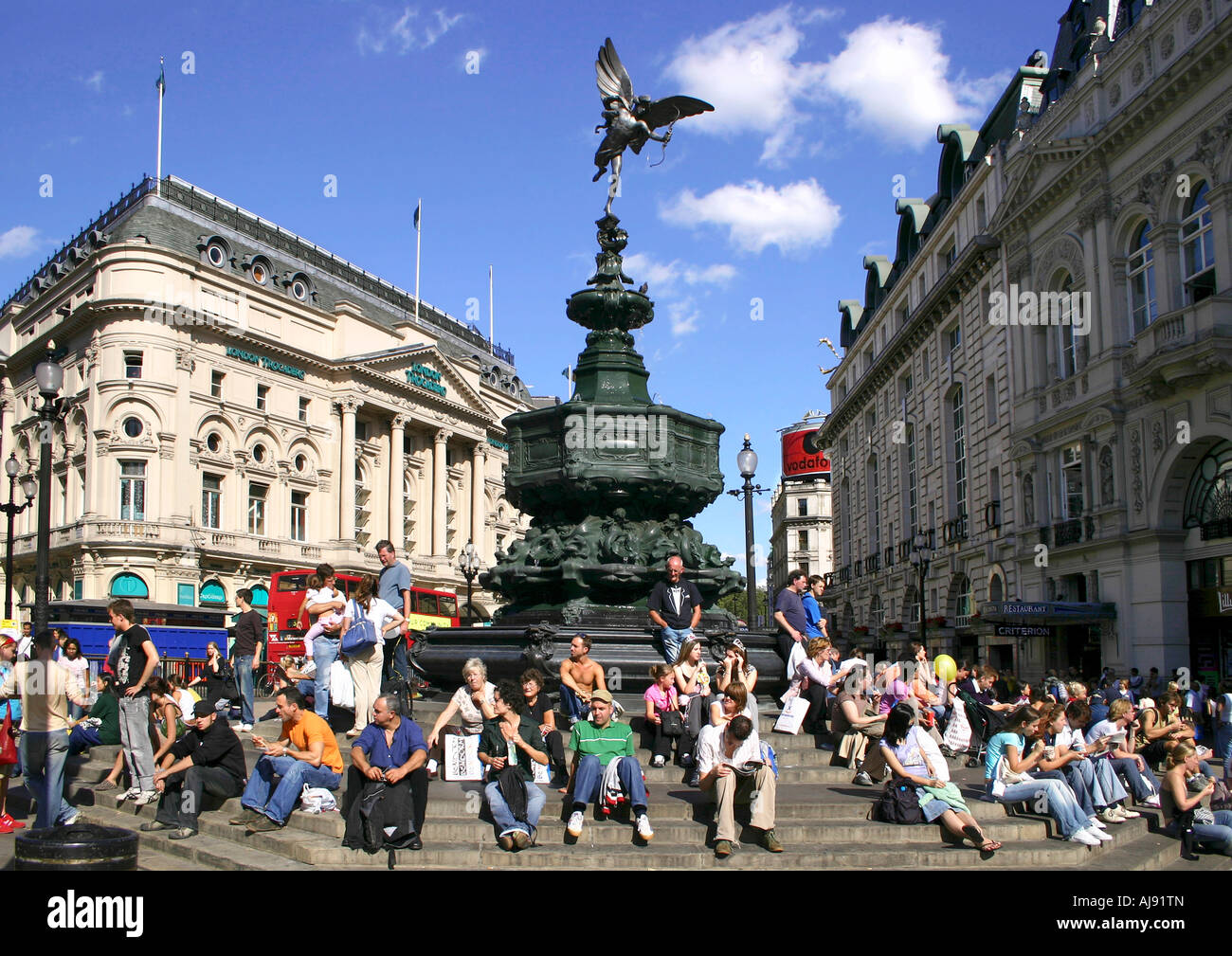Touristen sitzen durch die Statue des Eros, Piccadilly Circus, London, England Stockfoto