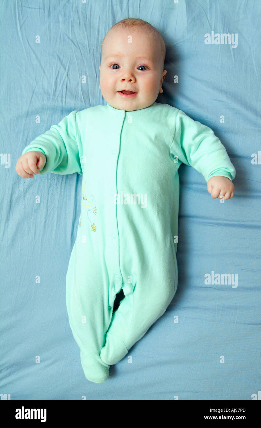 Baby Junge gekleidet in grünen Overall und liegen unten auf blauem Blatt Stockfoto