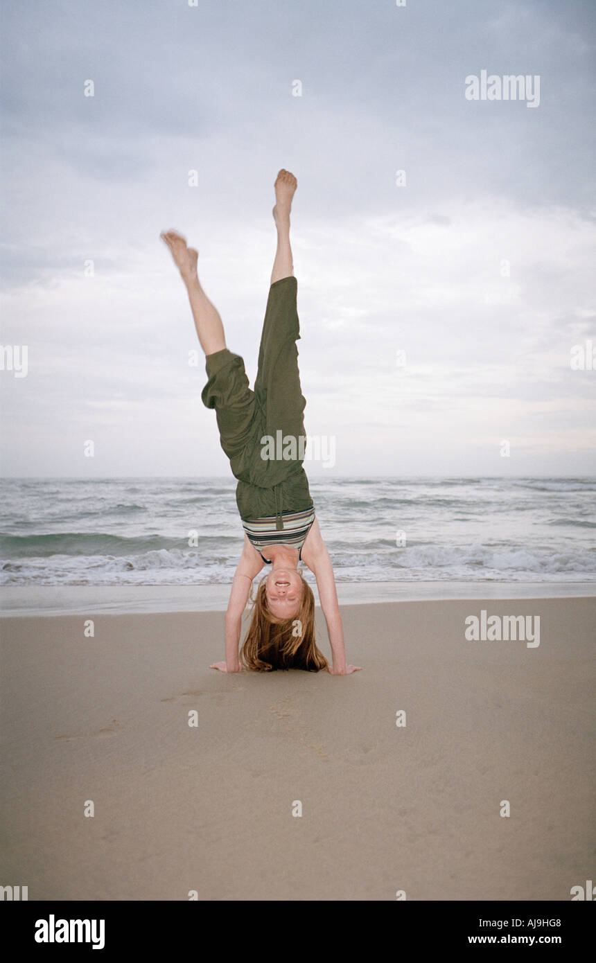 Junge Frau tun Handstand am Strand Stockfoto