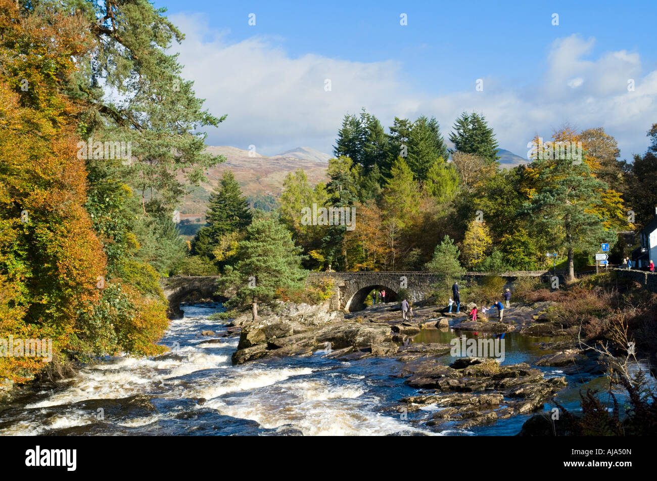 Mehrere kleine Wasserfälle Die Wasserfälle von Dochart auf dem Fluss Dochart bei Killin Schottland mit dem Fluss Dochart Brücke an einem sonnigen Herbsttag Stockfoto