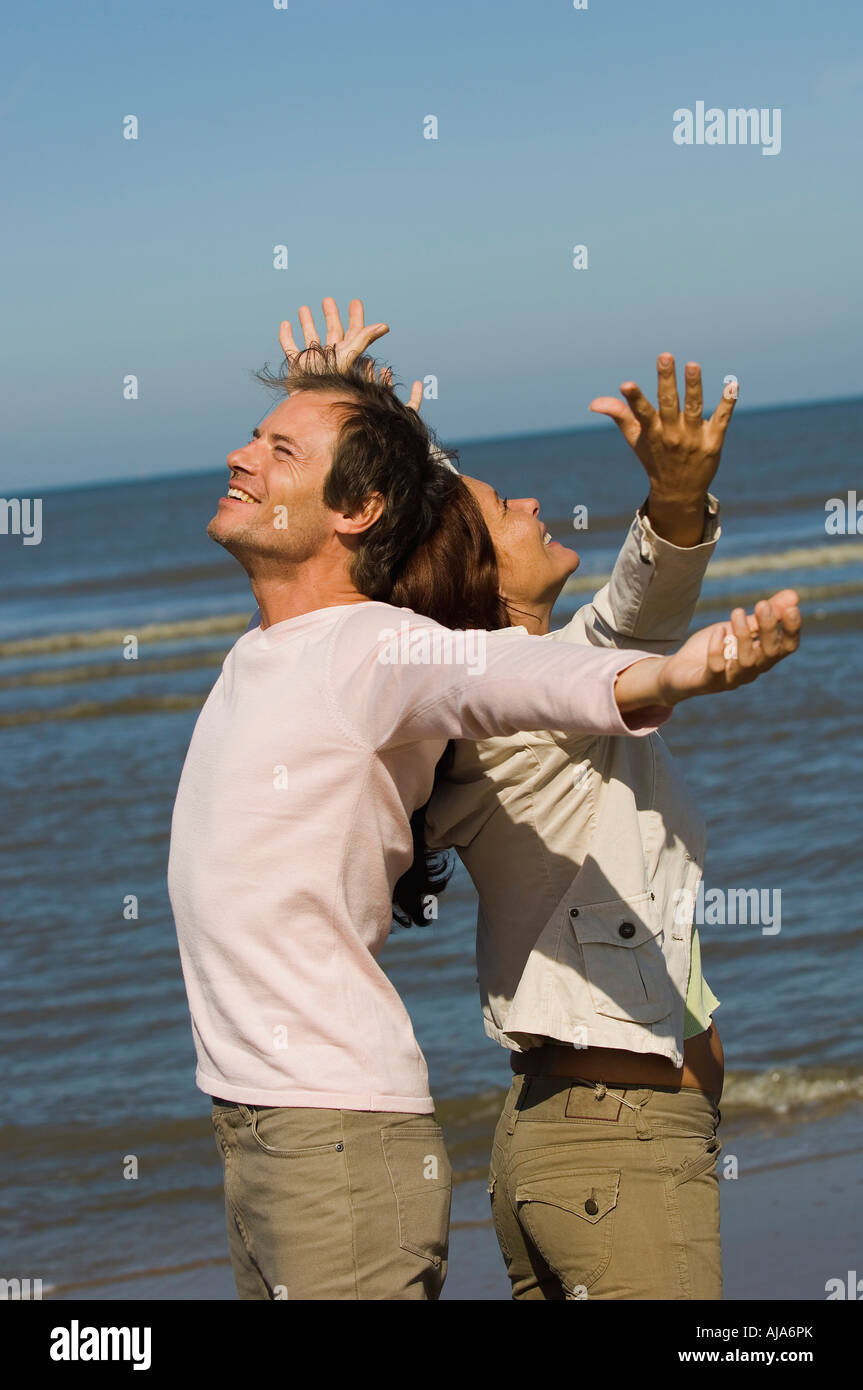 Mann und Frau mit Arme gestreckt am Strand Stockfoto