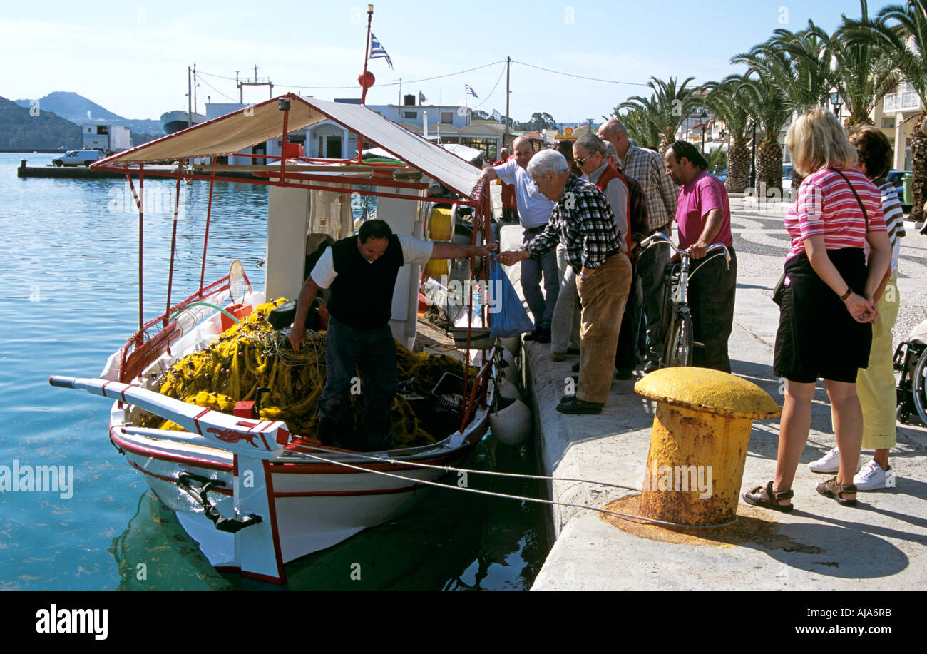 Mann kaufen Fisch vom Fischer am Fischerboot, Touristen auf Kai, Argostoli, Kefalonia, Griechenland Stockfoto