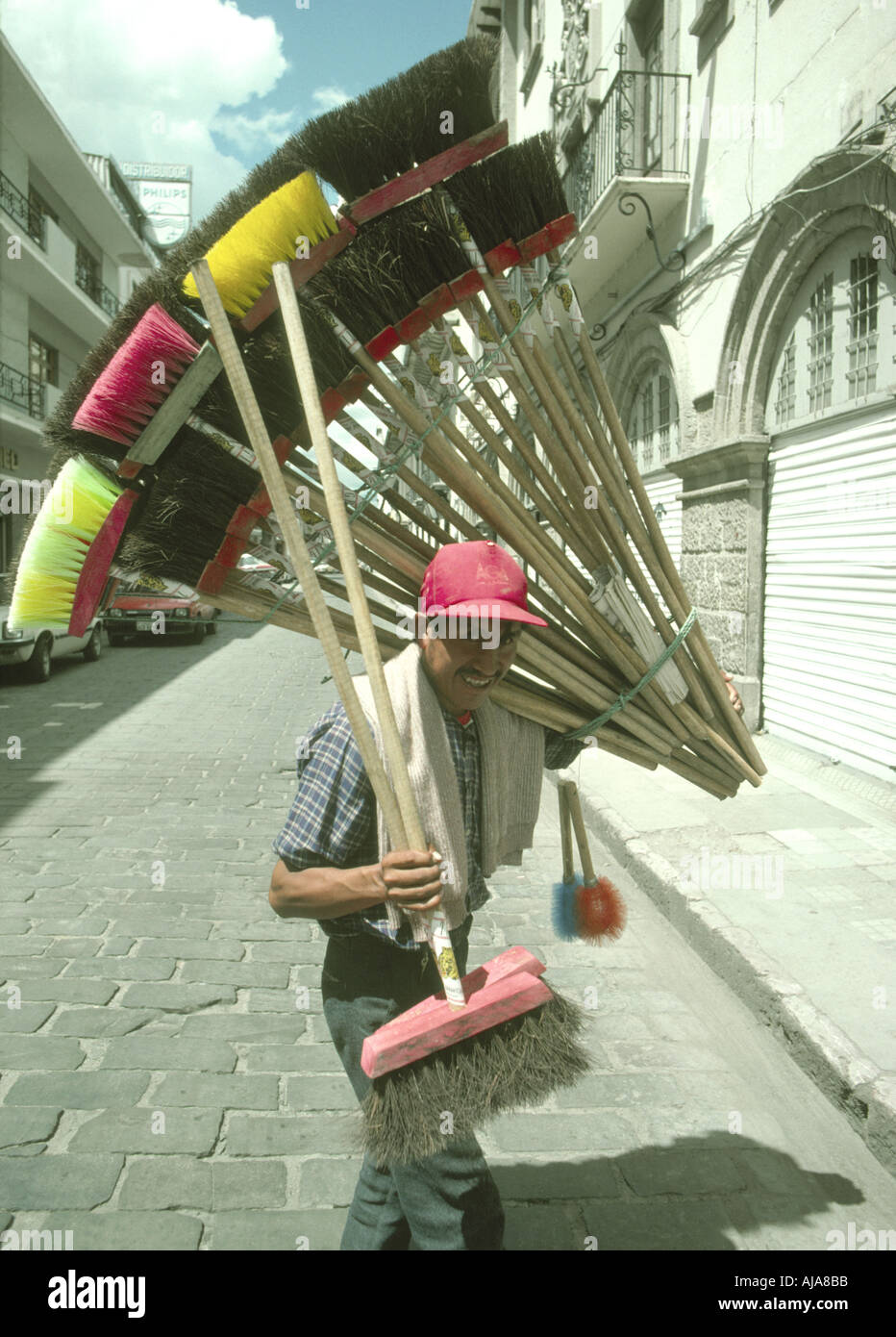 Ein Lächeln auf den Lippen Besen/Pinsel Verkäufer mit seinen bunten waren in einer Straße in Riobamba Ecuador Stockfoto