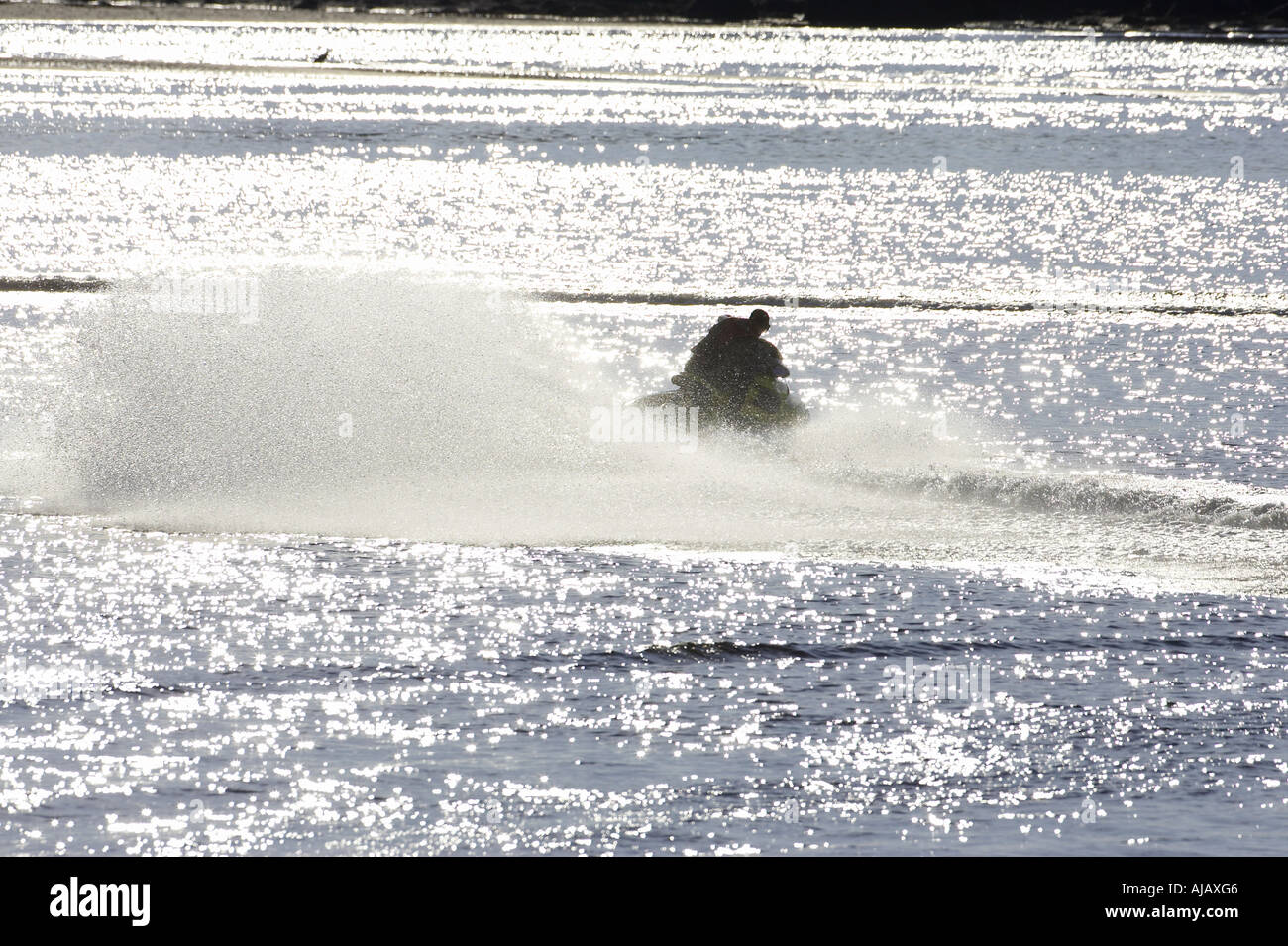 Silhouette der Mann im Anzug auf Bombardier Seadoo wendet sich rasch im Hafen von Bunbeg mit riesigen Spray und Gefolge hinter Stockfoto