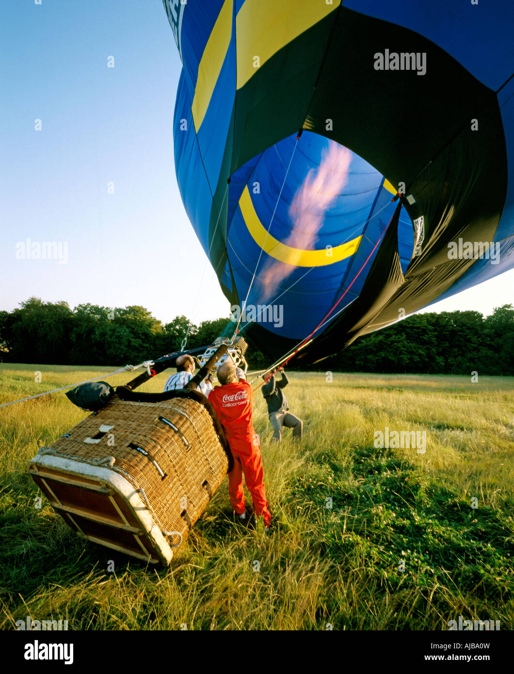 Ballonfahrer bläst heiße Gas aus Flammen Brenner in einem Heißluftballon an einem späten Sommerabend im Feld starten am Abend HXXZsmng Stockfoto