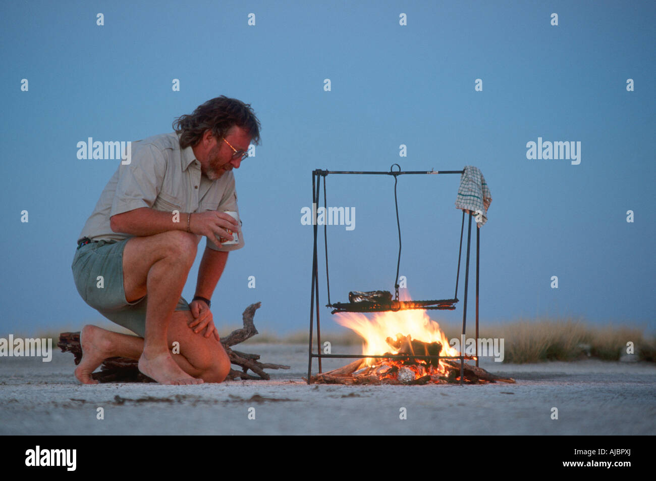 Mann Kochen auf offenem Feuer auf der Makgadikgadi Salzpfannen Stockfoto
