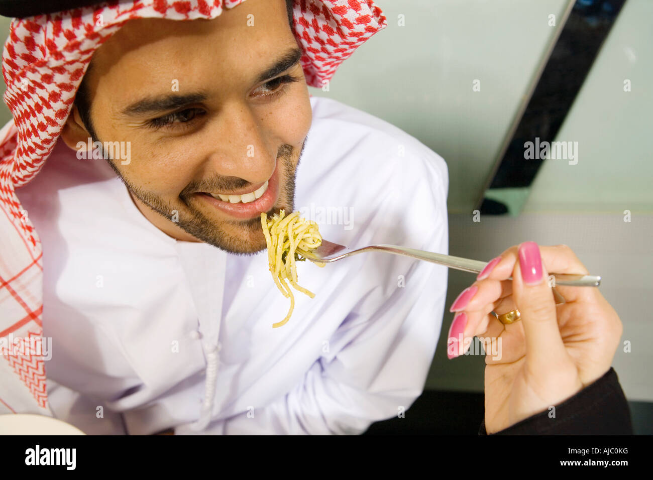 Arabische Frau füttert lächelnden Mann Spaghetti, High Angle View Stockfoto