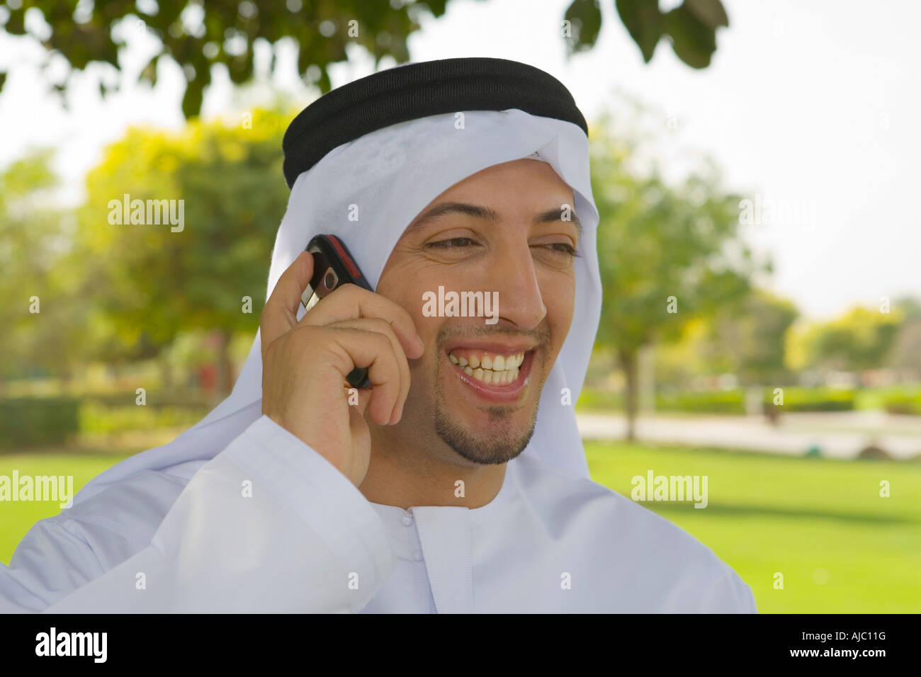 Arabische Mann Lachen auf dem Handy im Park, gerichtete Kamera Stockfoto