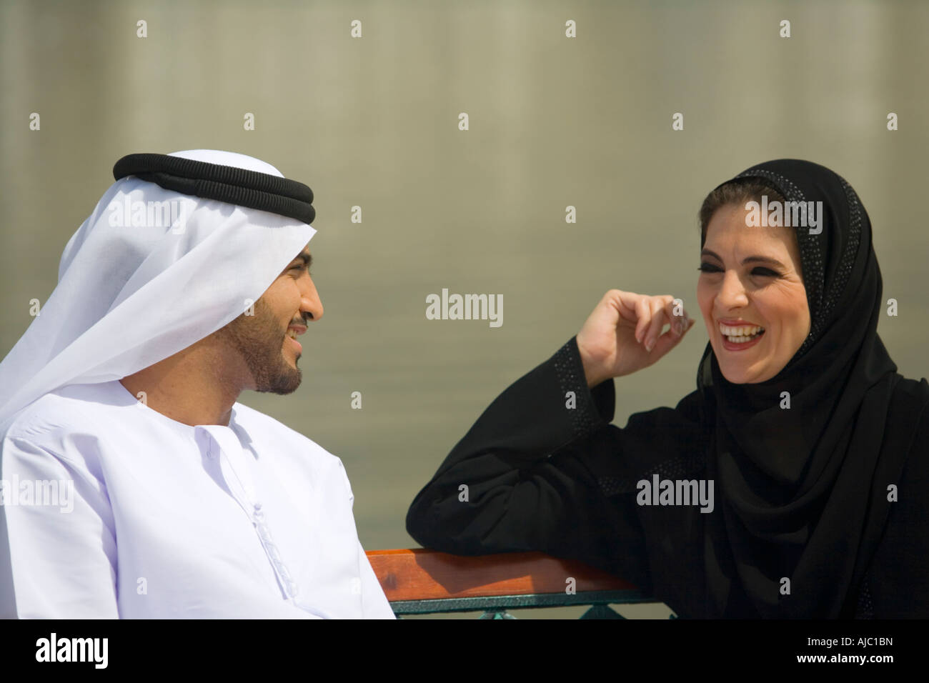 Arabische Mann und Frau lachend auf Parkbank Stockfoto