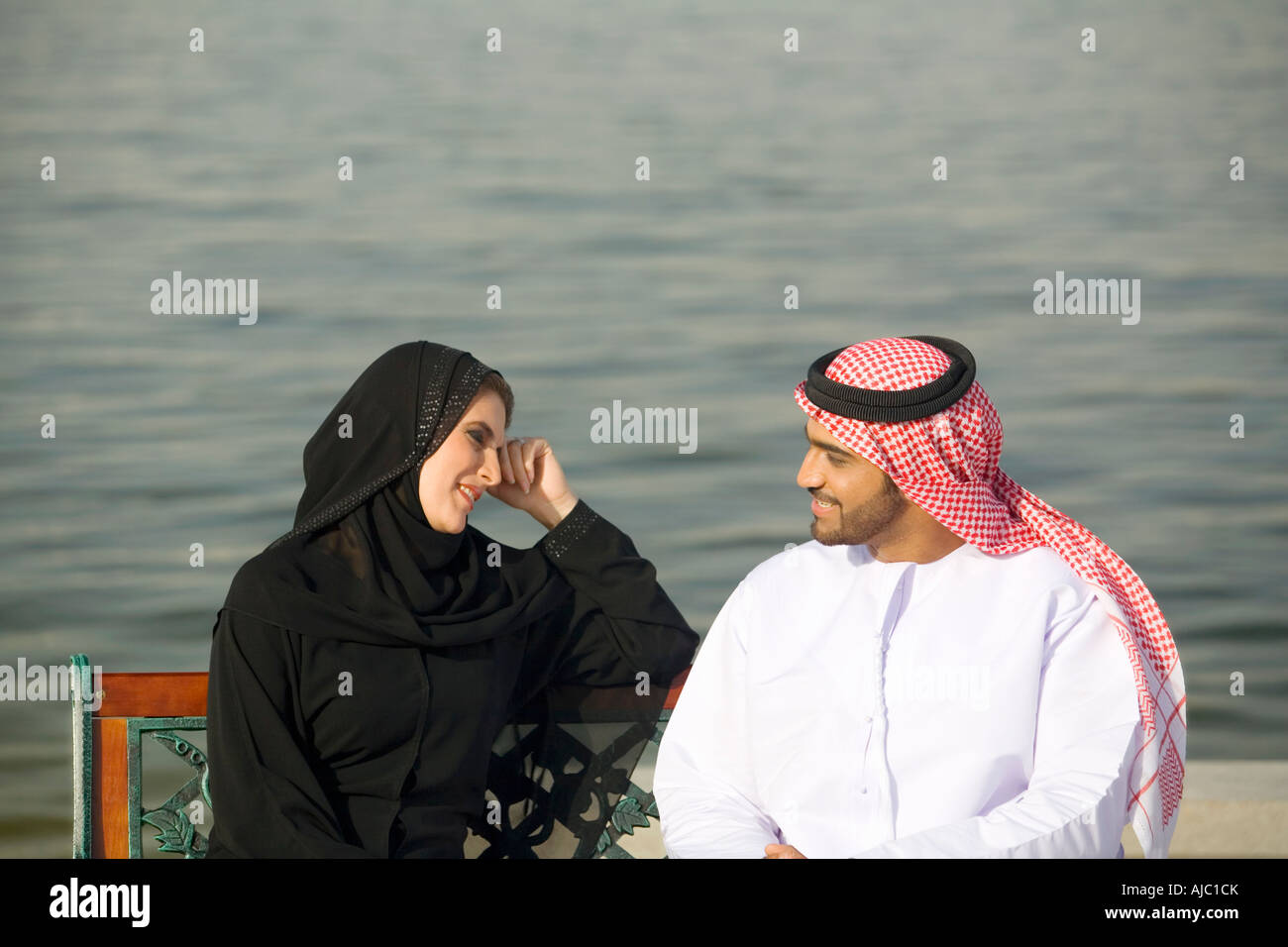 Arabische Mann und Frau sitzen auf der Parkbank am Meer, Profil-Seitenansicht Stockfoto